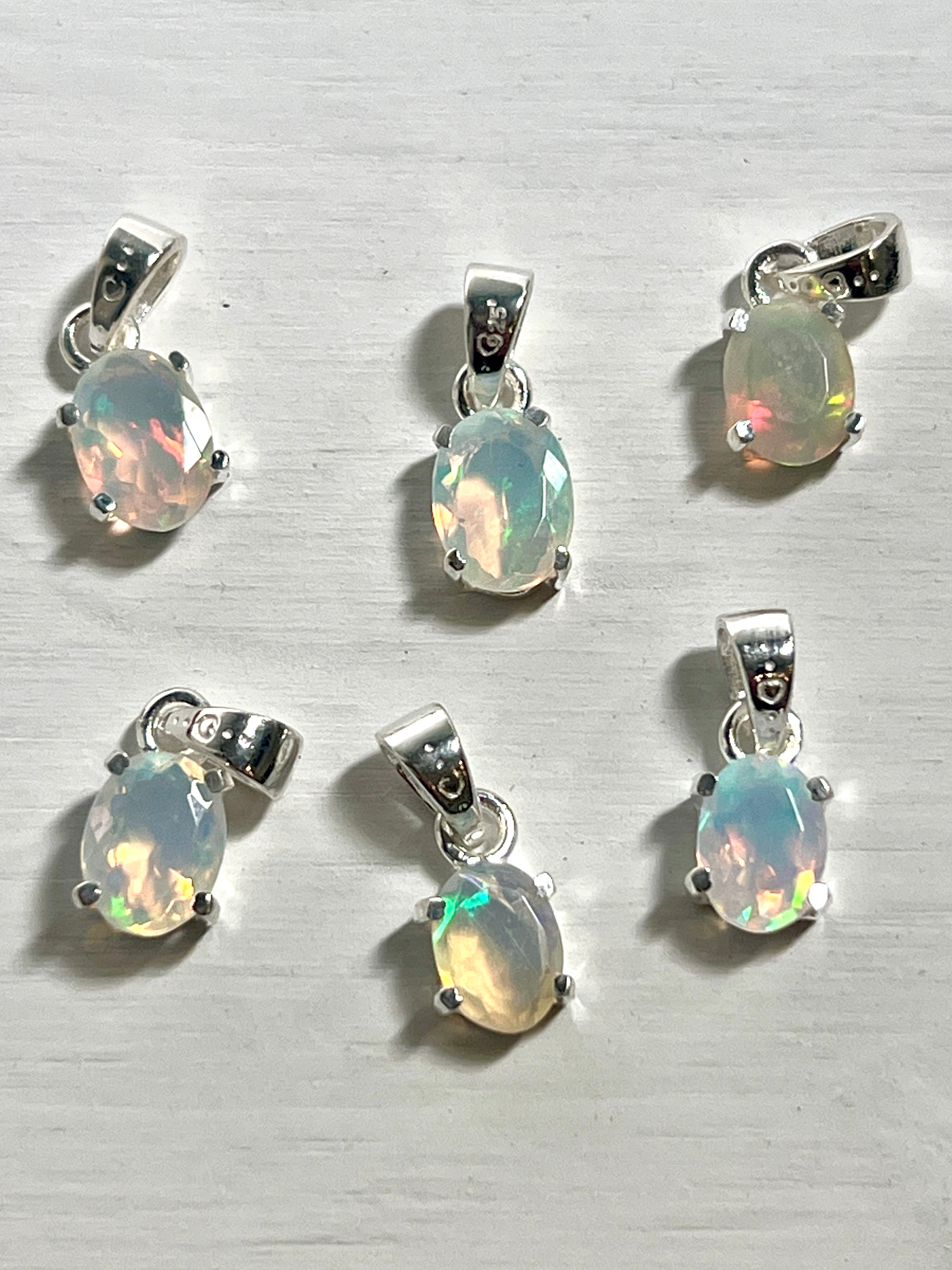Six Tiny Facet Cut Prong Set Ethiopian Opal Pendants with Super Silver on a white surface.