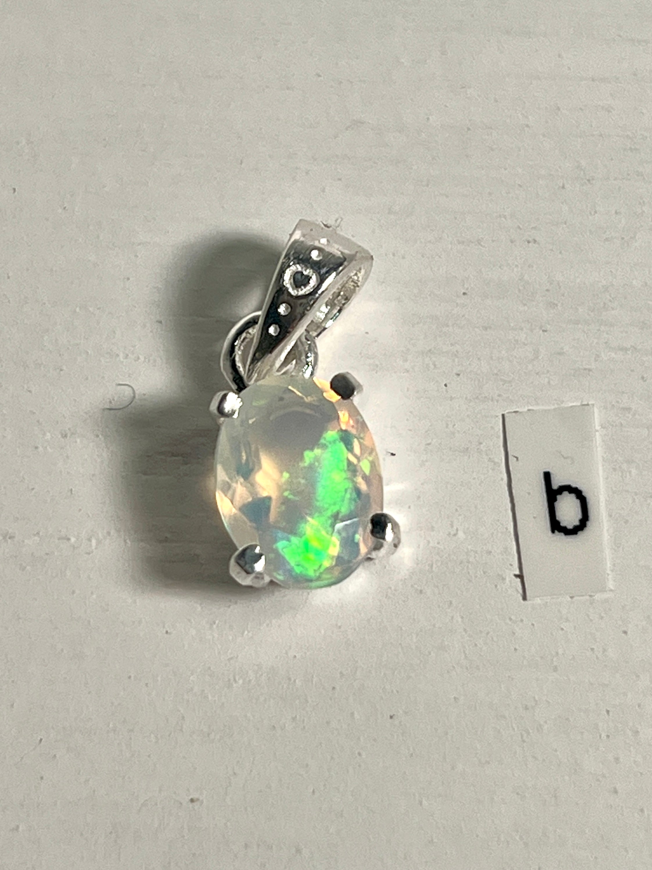 A Tiny Facet Cut Prong Set Ethiopian Opal Pendant by Super Silver with the letter B intricately engraved on it.