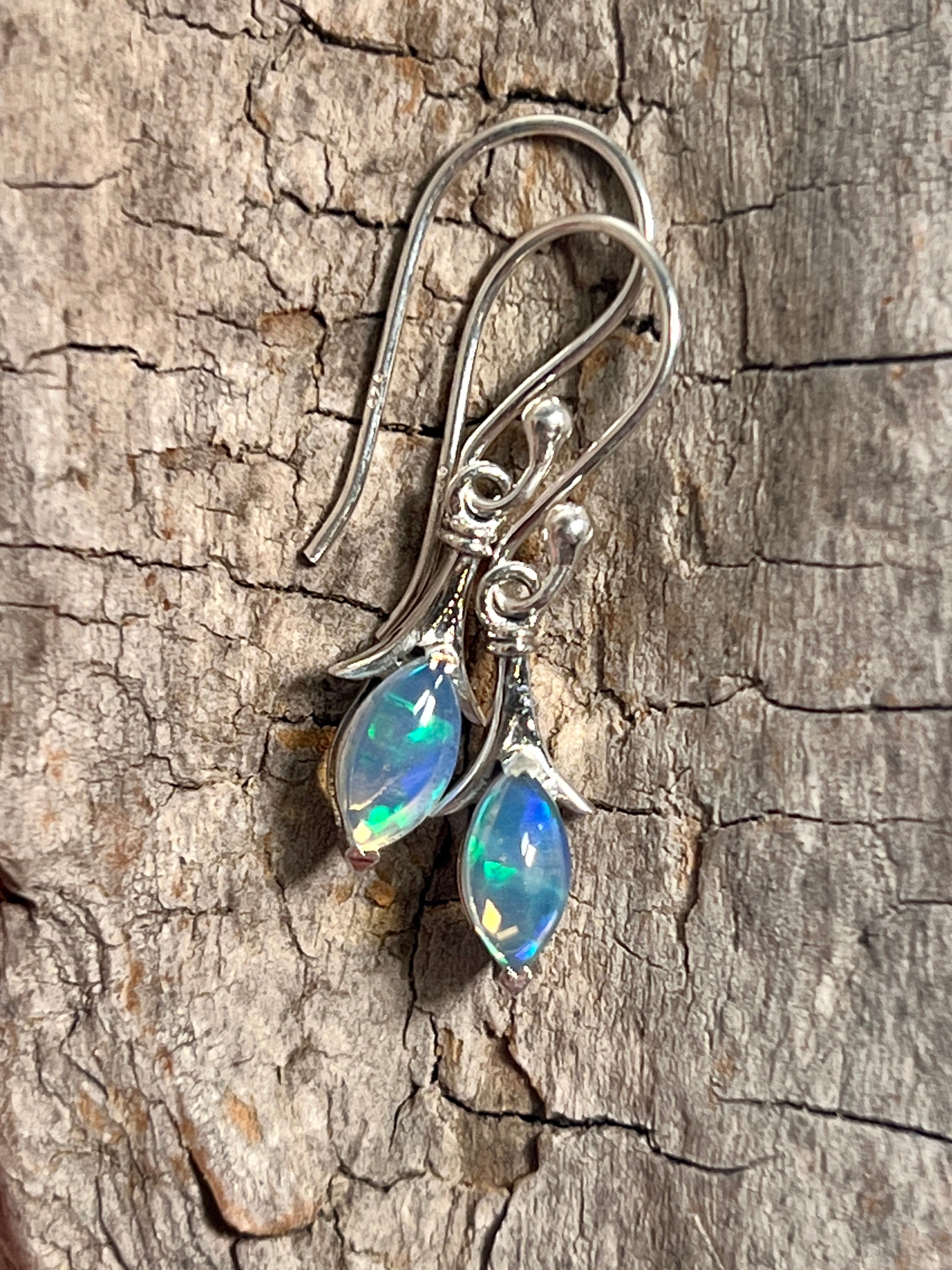 A pair of Modern Marquise Shaped Ethiopian Opal Earrings by Super Silver on a piece of wood.
