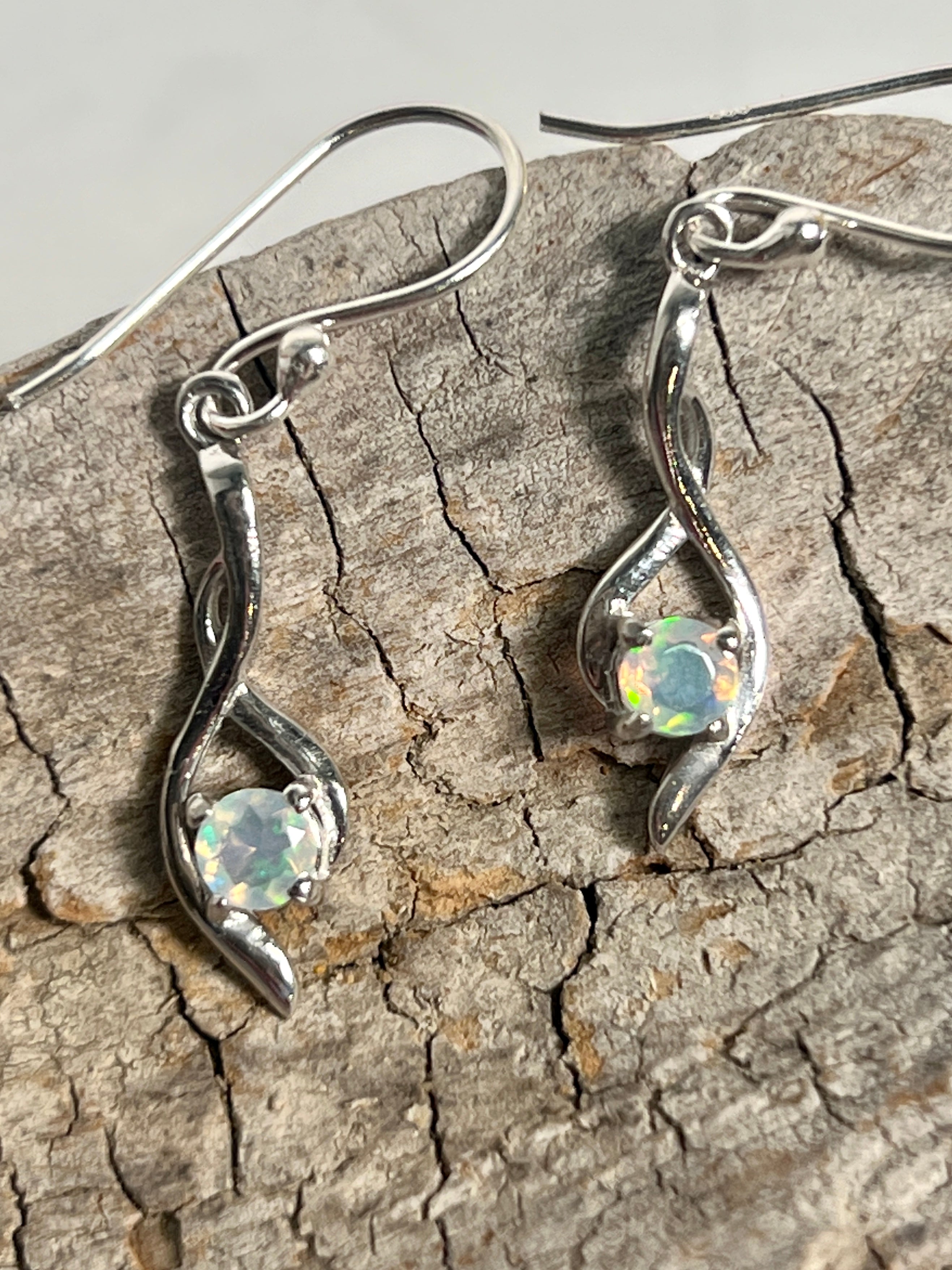 A pair of glamorous Modern Ethiopian Opal earrings by Super Silver on a piece of wood.