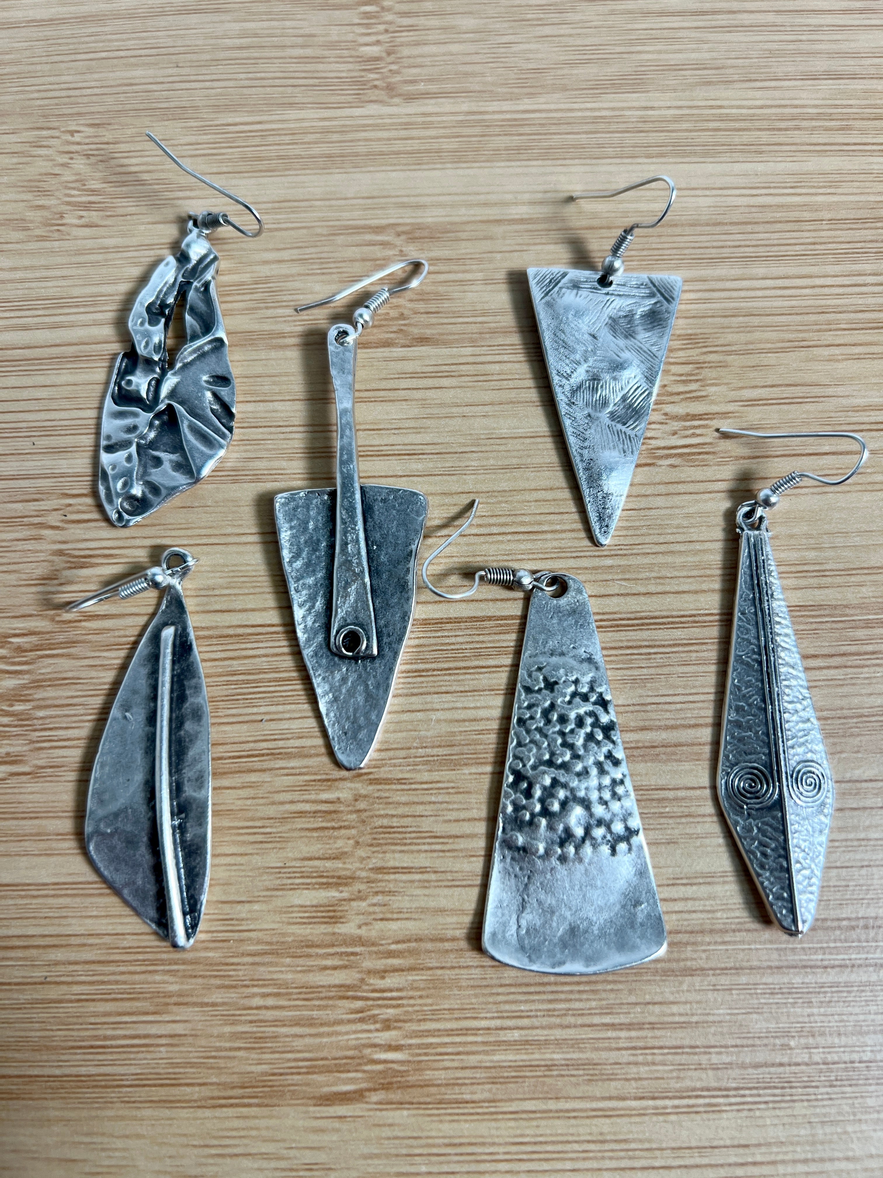A group of Triangular Boho Statement Earrings by Super Silver on a wooden table.