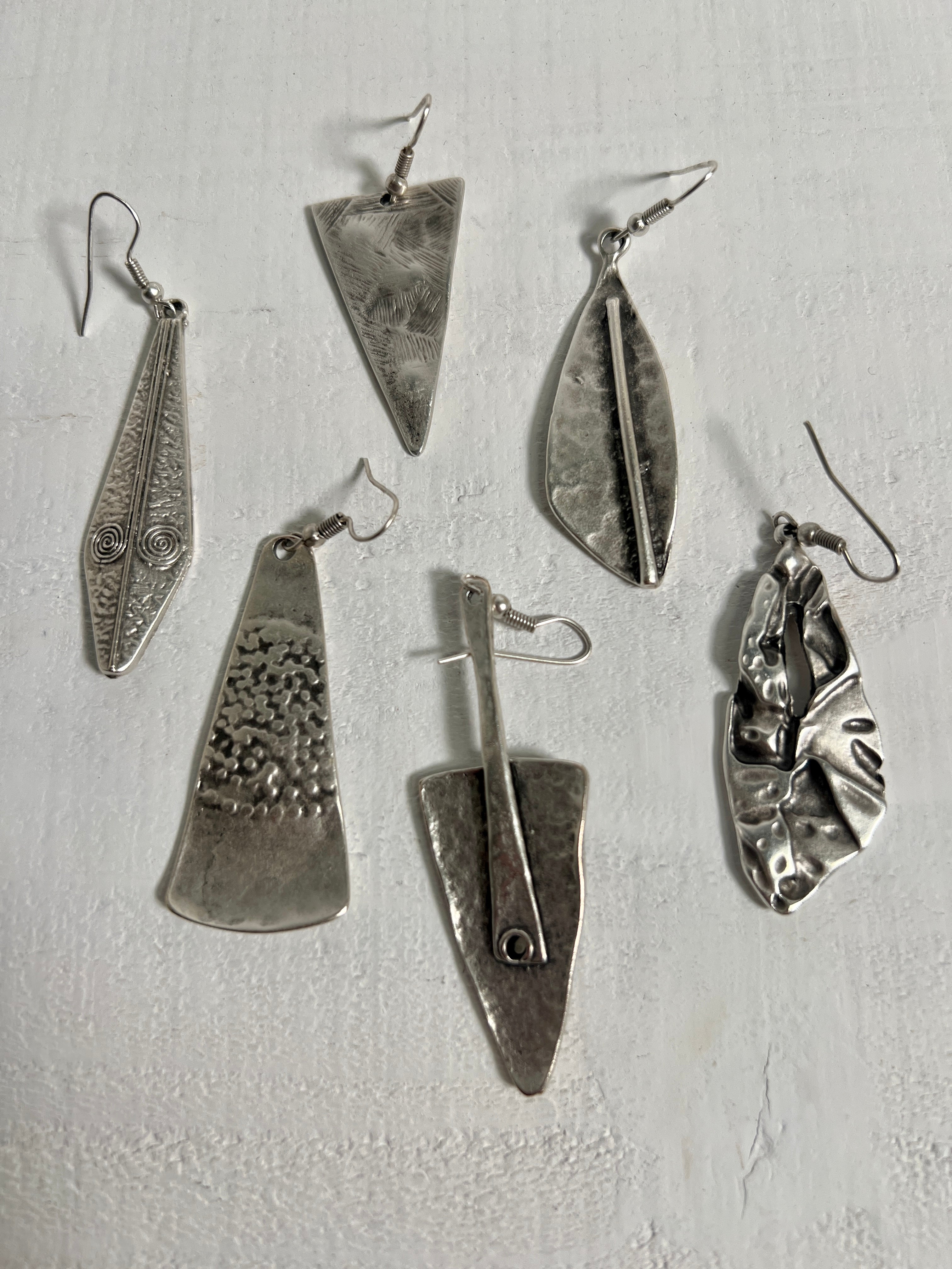 A collection of Super Silver's Triangular Boho Statement Earrings, made of Zamak, arranged elegantly on a pristine white surface.