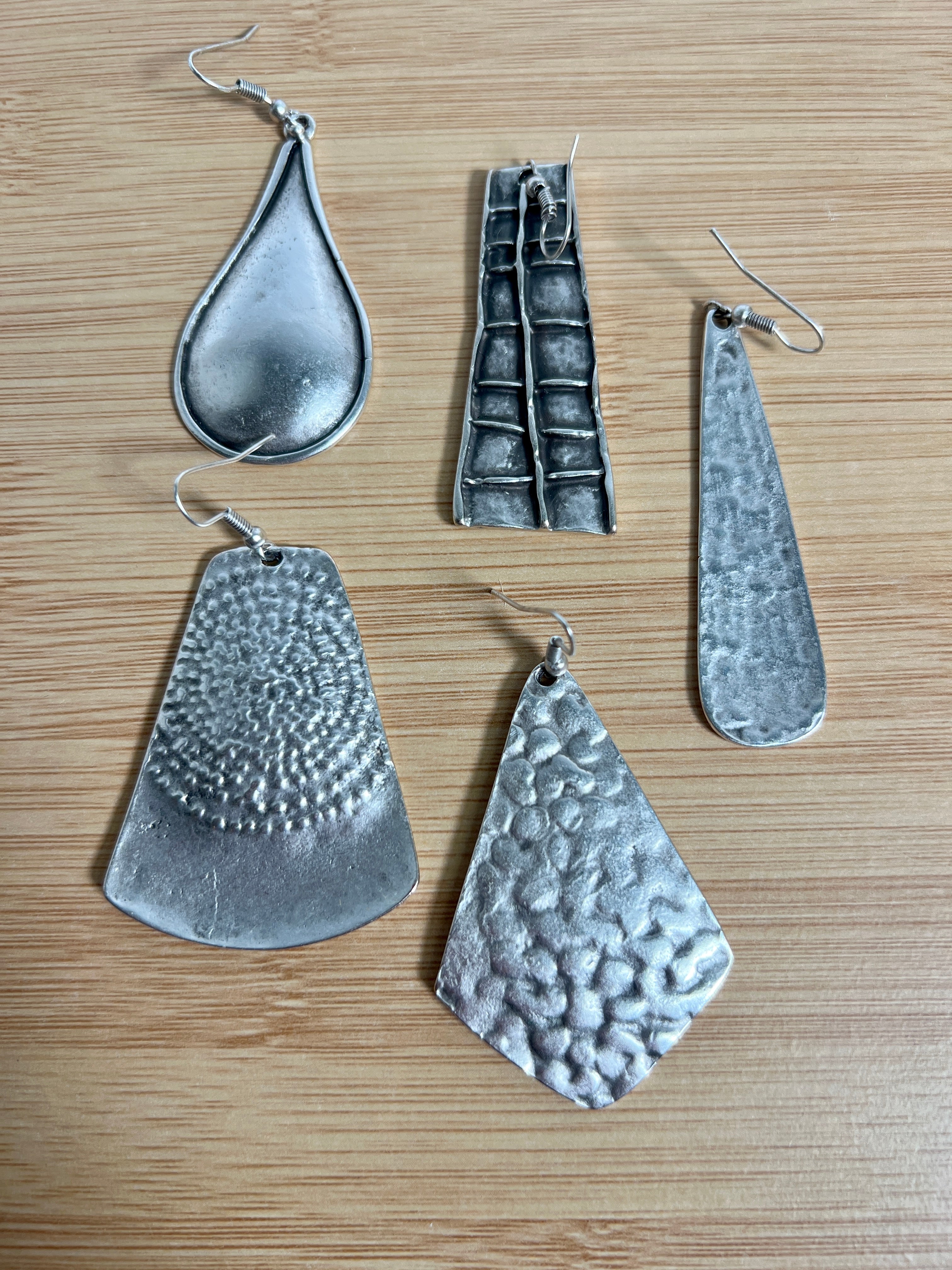 A group of dramatic Super Silver Long Boho Statement Earrings on a wooden table.