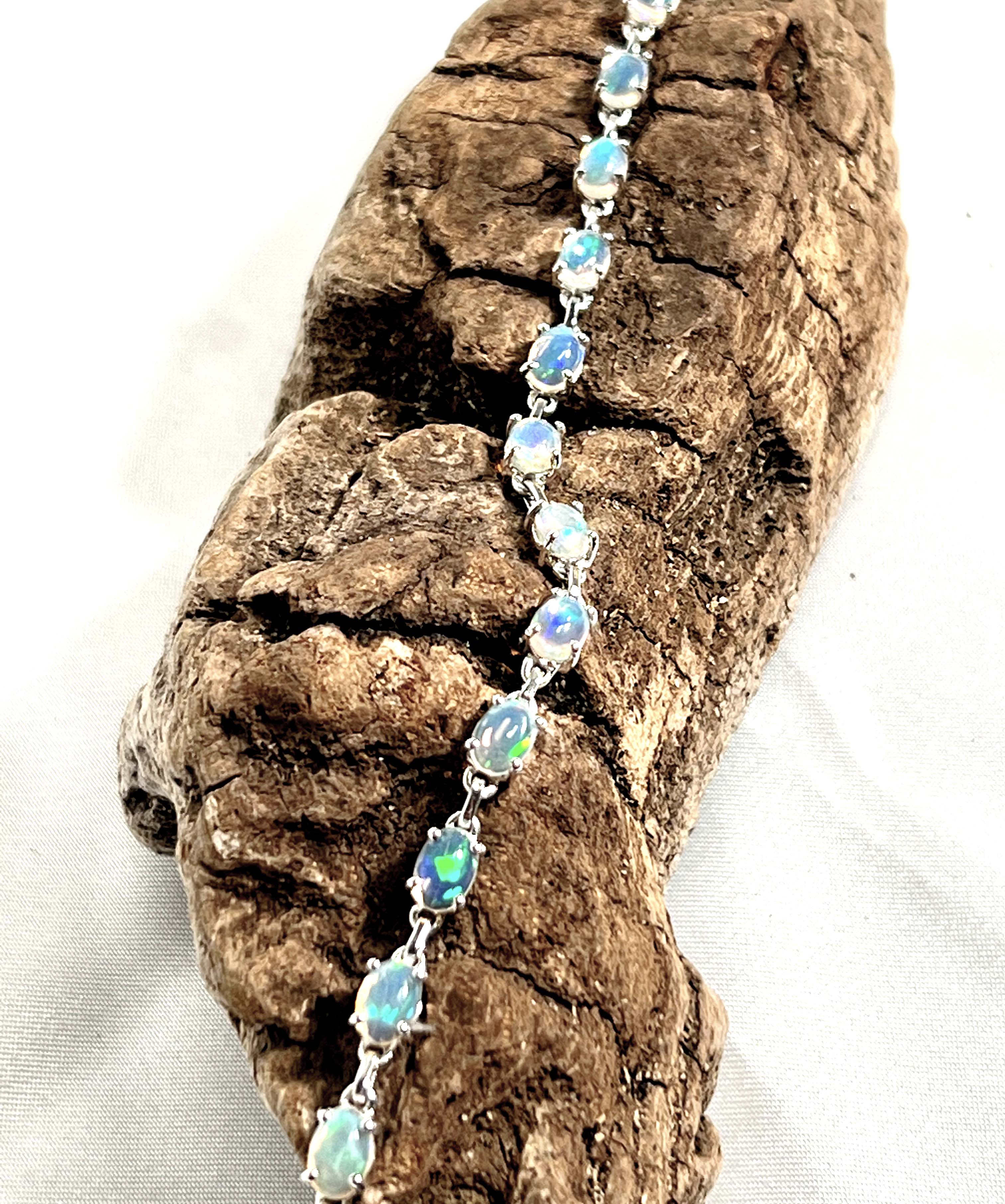 A glamorous Delicate Ethiopian Opal bracelet from Super Silver resting on a rustic piece of wood.