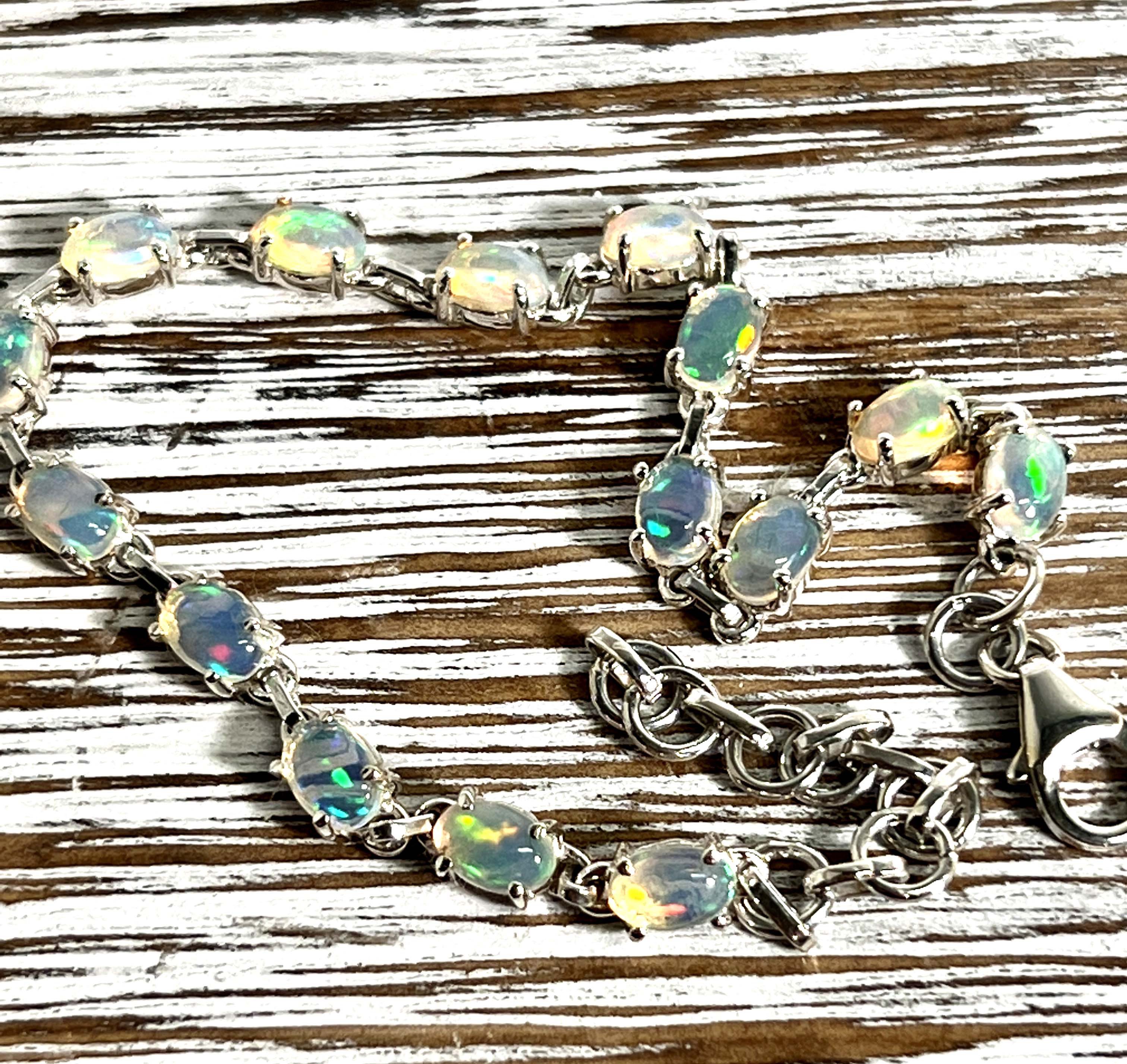 A glamorous Delicate Ethiopian Opal Super Silver bracelet shines brilliantly on a wooden table.