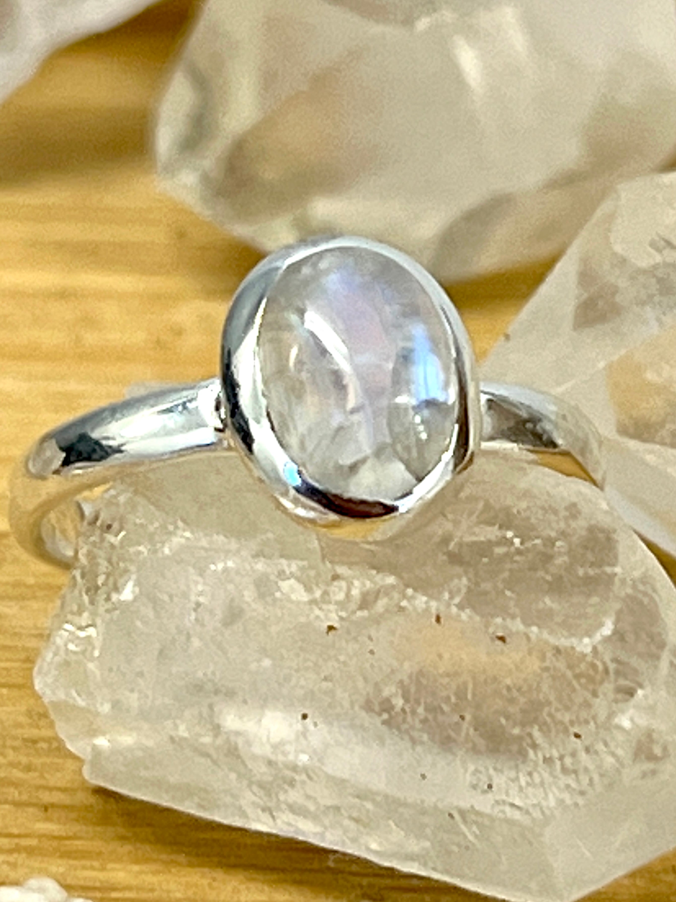 A Simple Oval Moonstone Or Labradorite Ring featuring a moonstone cabochon atop crystals.