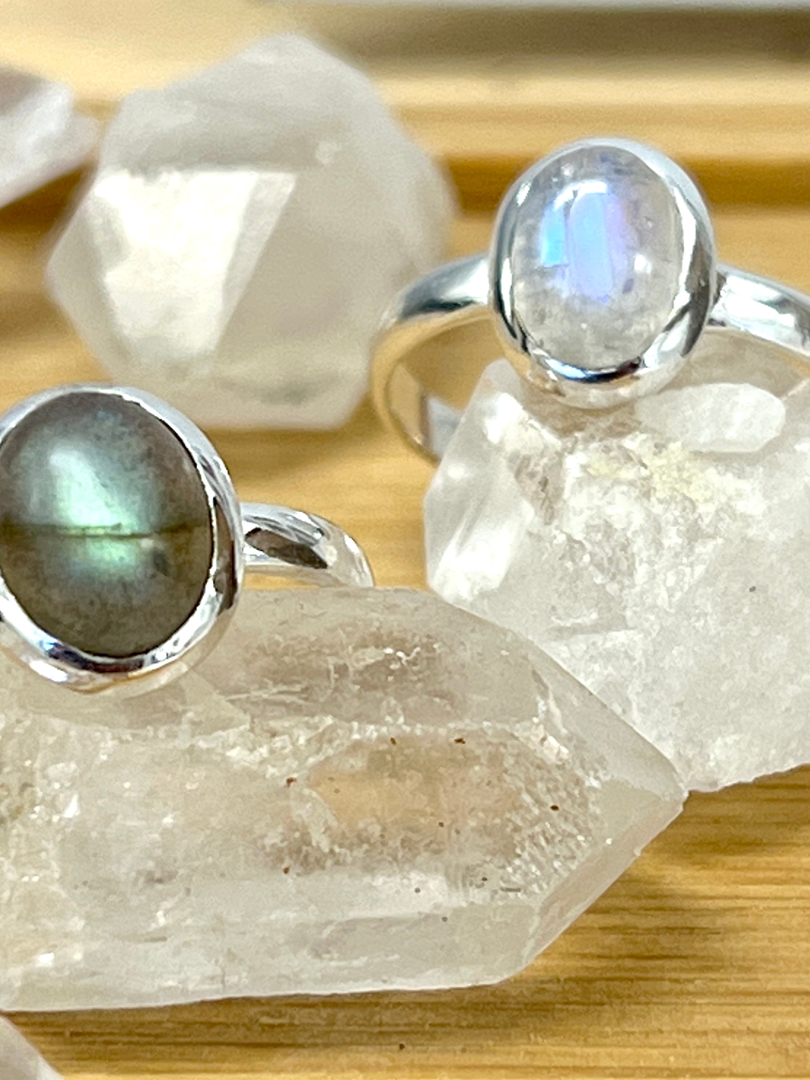 Two sterling silver Simple Oval Moonstone Or Labradorite Rings on top of a table.