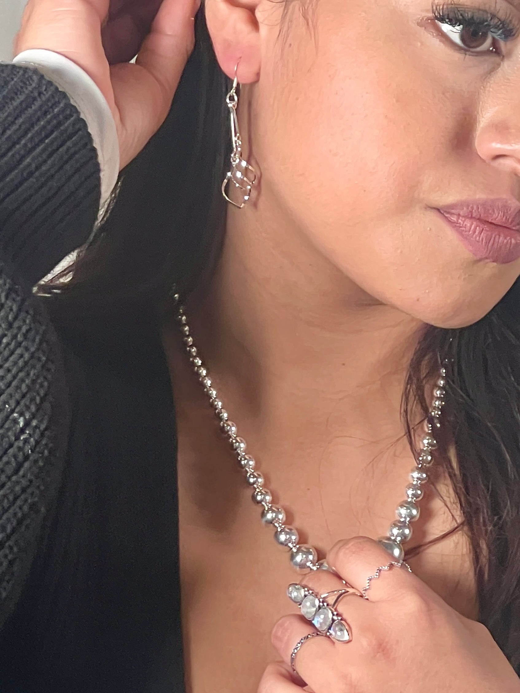 A woman wearing Super Silver's Delicate Twisted Freeform Earrings and a necklace.