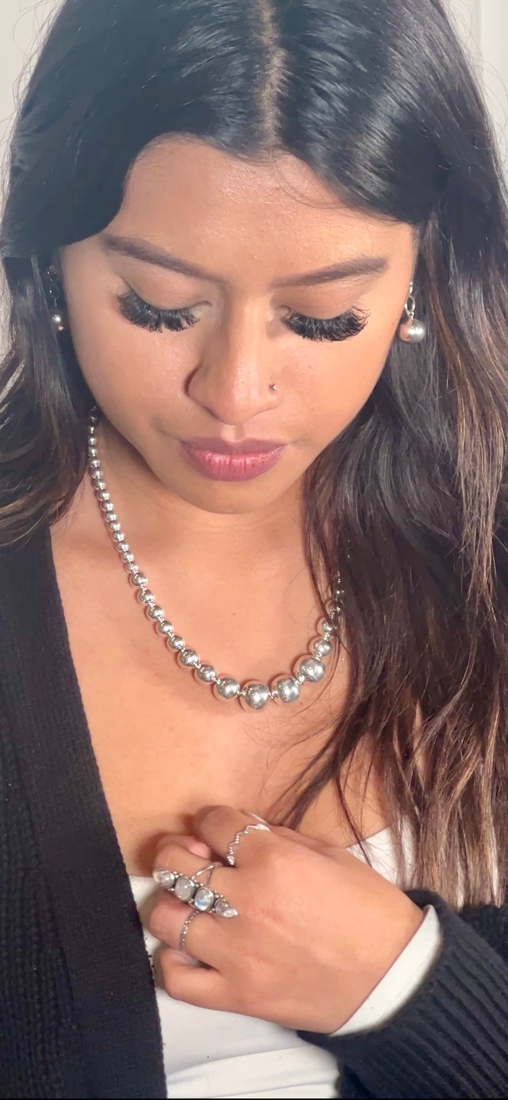 A woman wearing a Super Silver Graduated Silver Bead Necklace and a silver beaded ring.