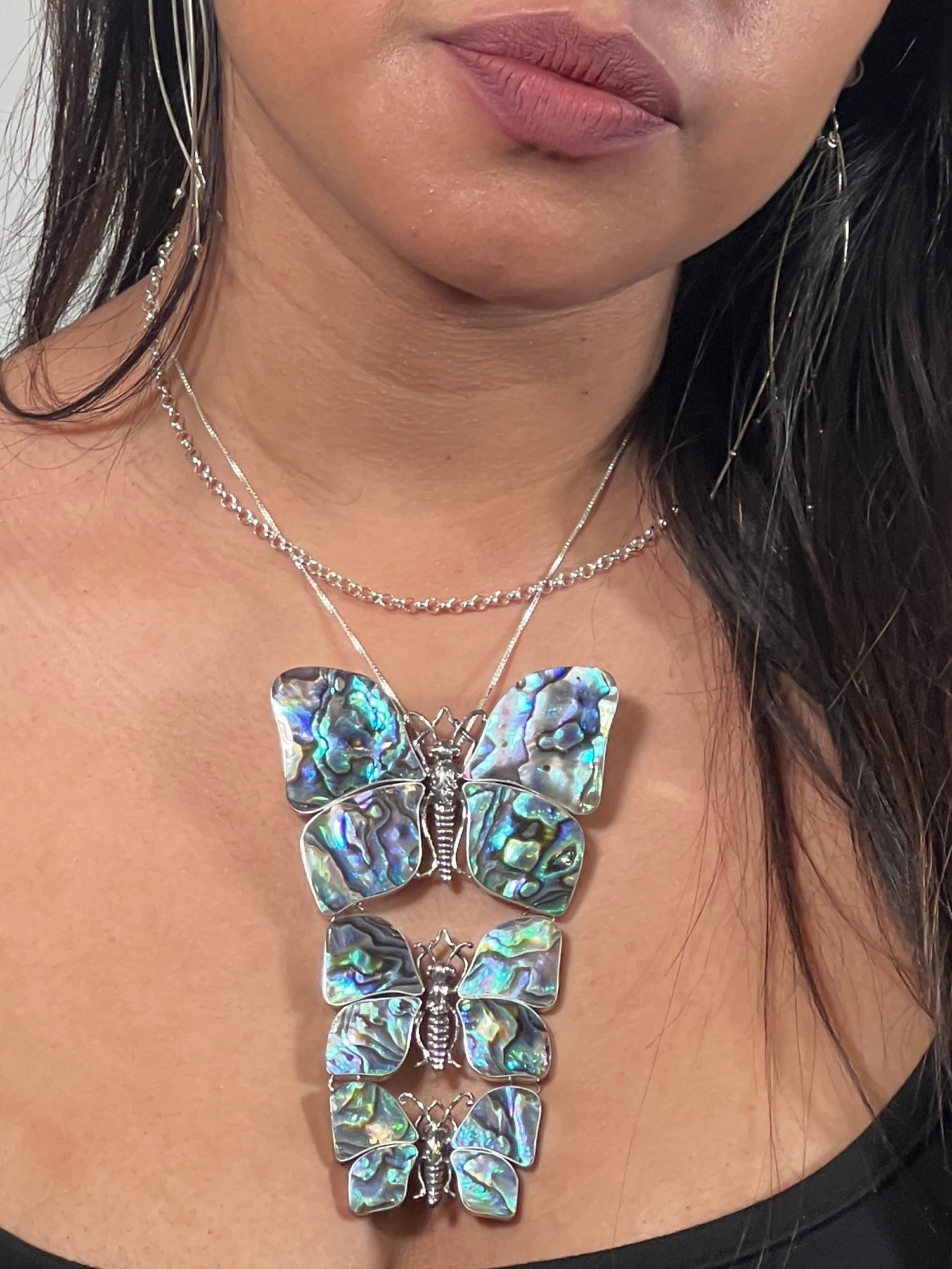 A nature lover's delight, this woman is adorned with a Statement Pendant or Brooch with Three Butterflies, each with detailed abalone shell wings, on a thin silver chain.