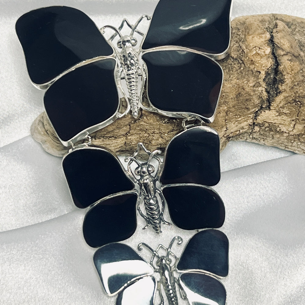 
                  
                    Three stunning Super Silver black butterfly pendants delicately arranged on a piece of wood, creating a captivating statement for any nature lover.
                  
                