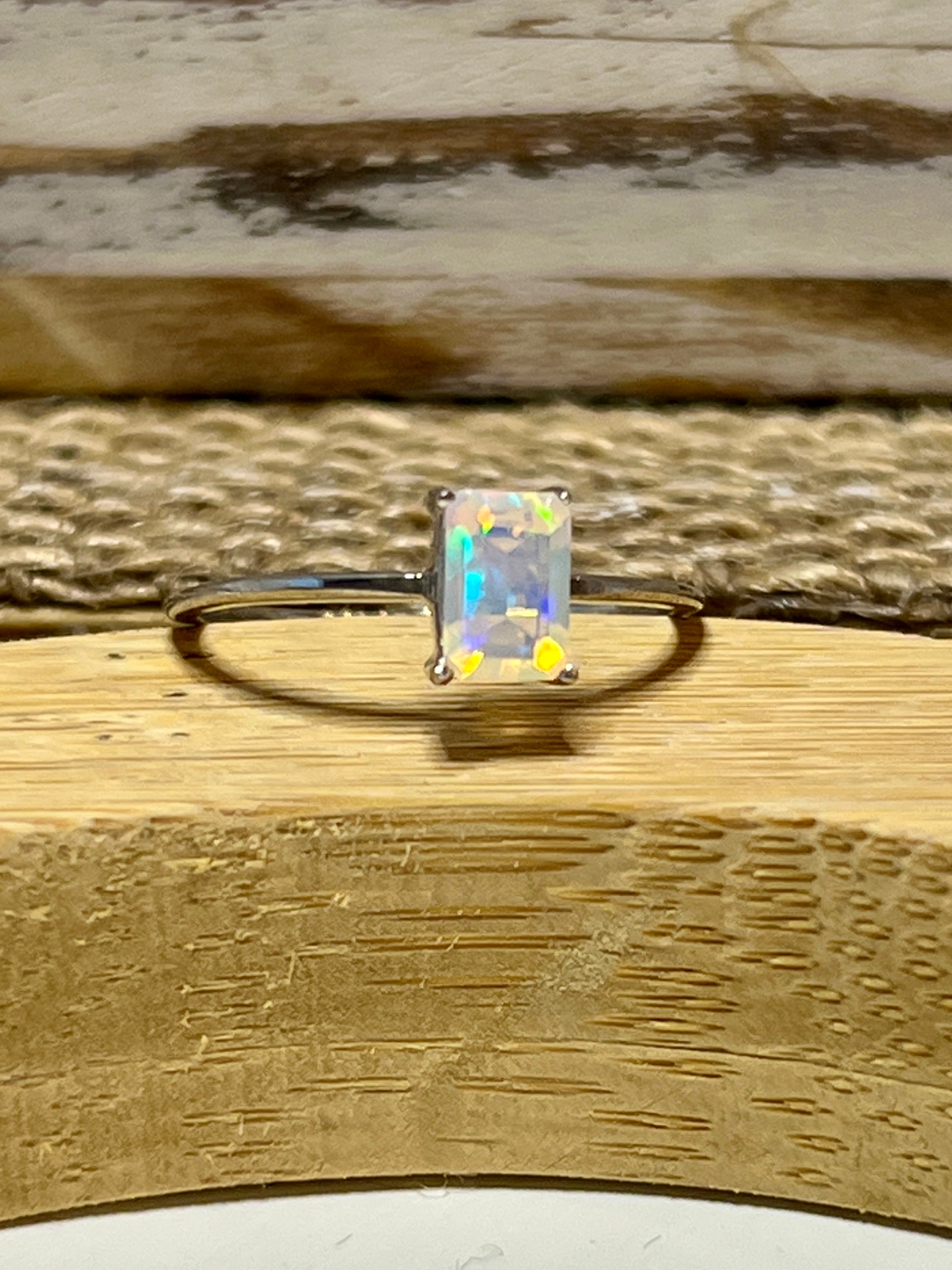 A Cushion Cut Ethiopian Opal ring sitting on top of a wooden table.
