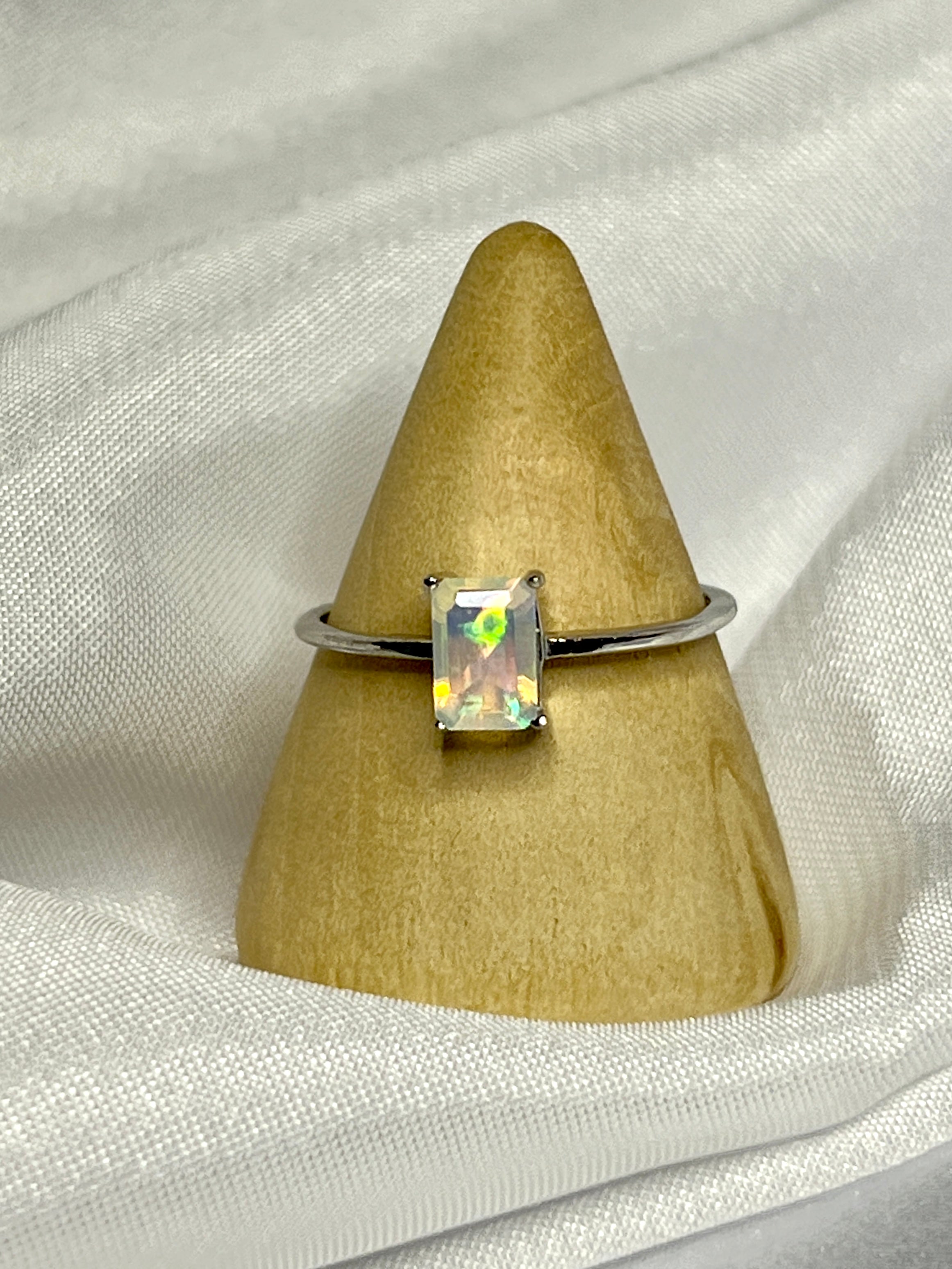 A Cushion Cut Ethiopian Opal ring displayed on top of a white cloth.