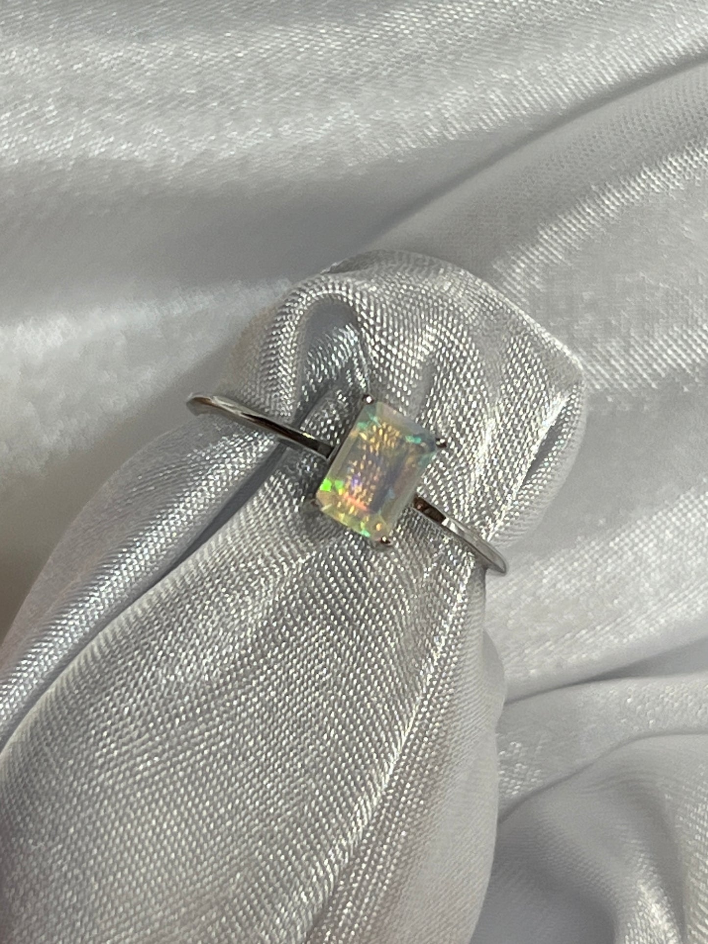 A cushion cut Ethiopian opal ring sitting on a white cloth.