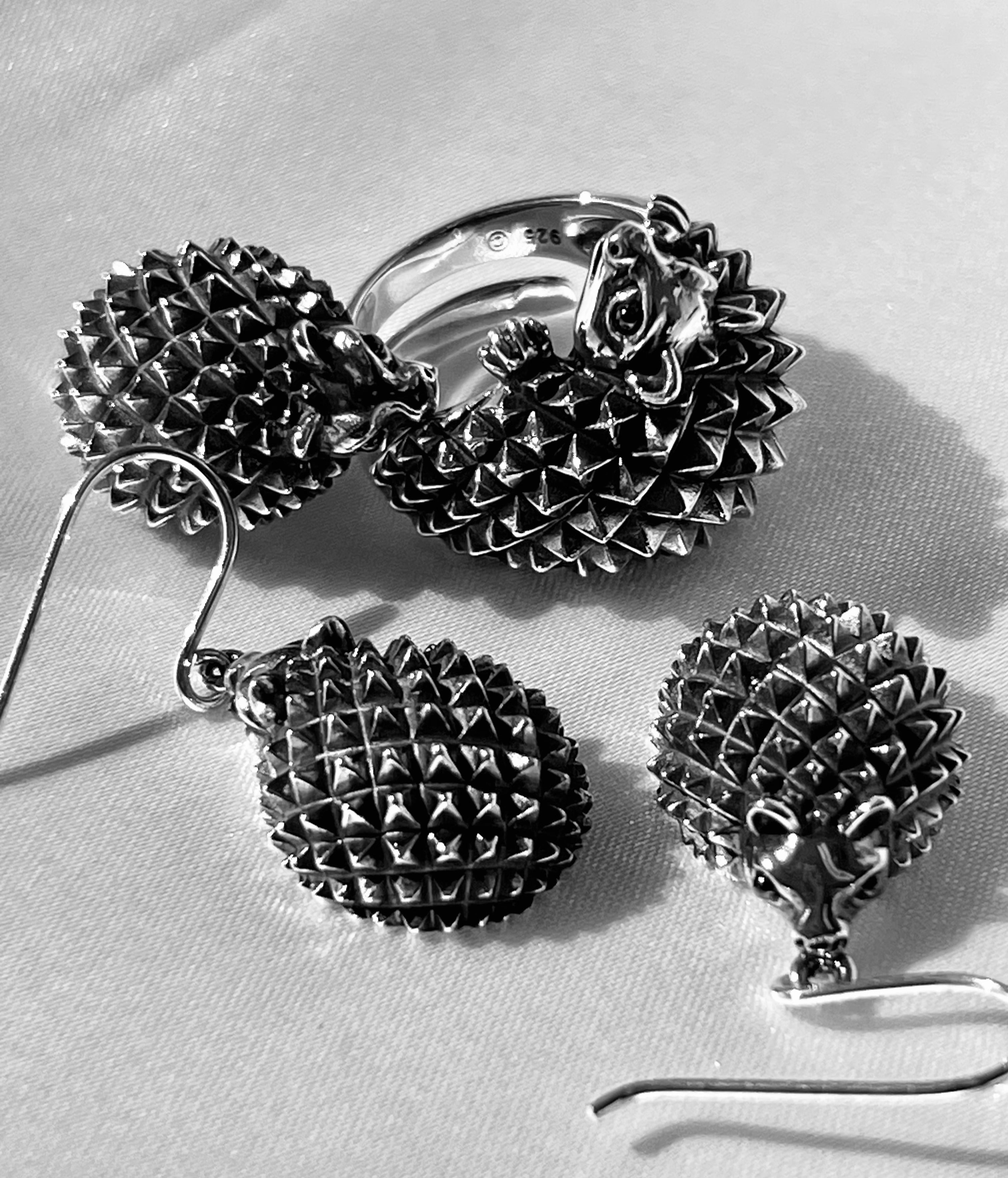 A vintage black and white photo showcasing a Super Silver Hedgehog Pendant and Brooch.