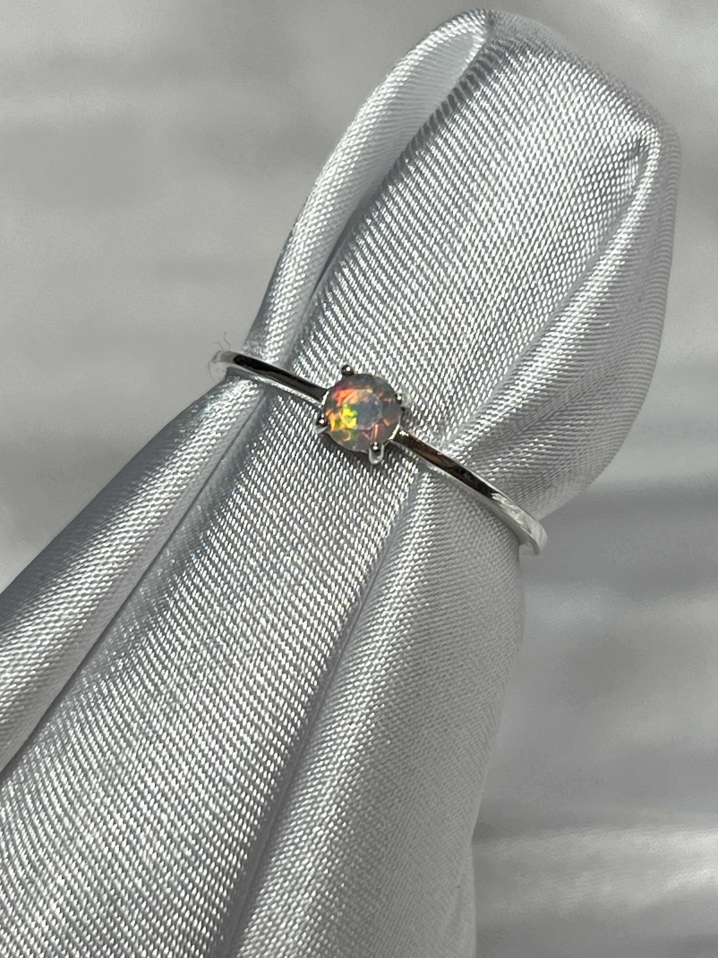 An elegant silver Dainty Prong Set Facet Cut Ethiopian Opal engagement ring with a captivating opal stone.