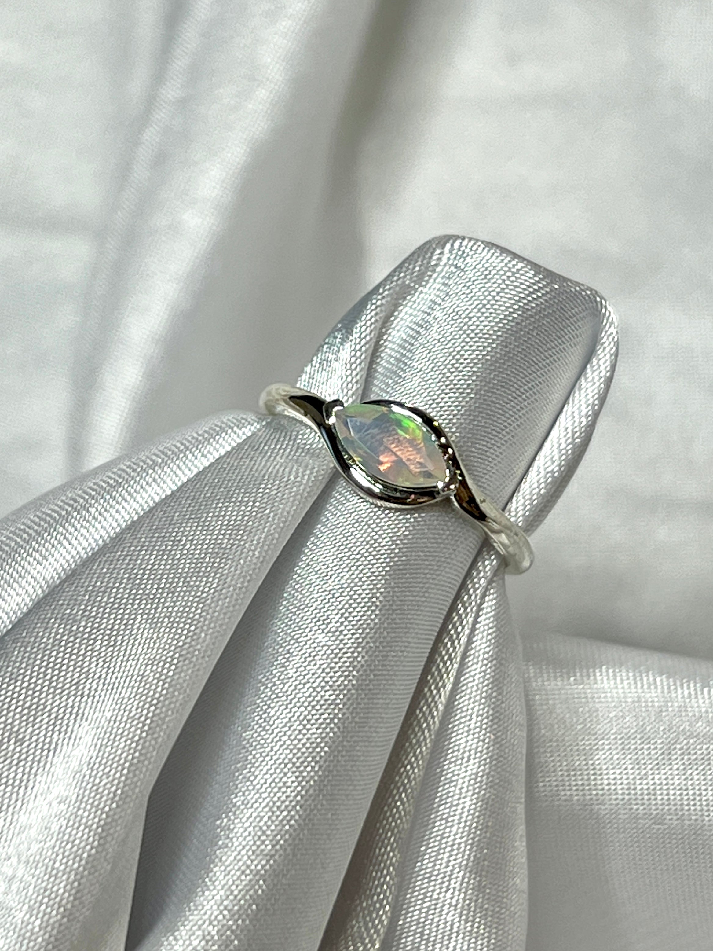 A Brilliant Facet Cut Ethiopian Opal ring making a statement as it rests gracefully on a pristine white cloth.