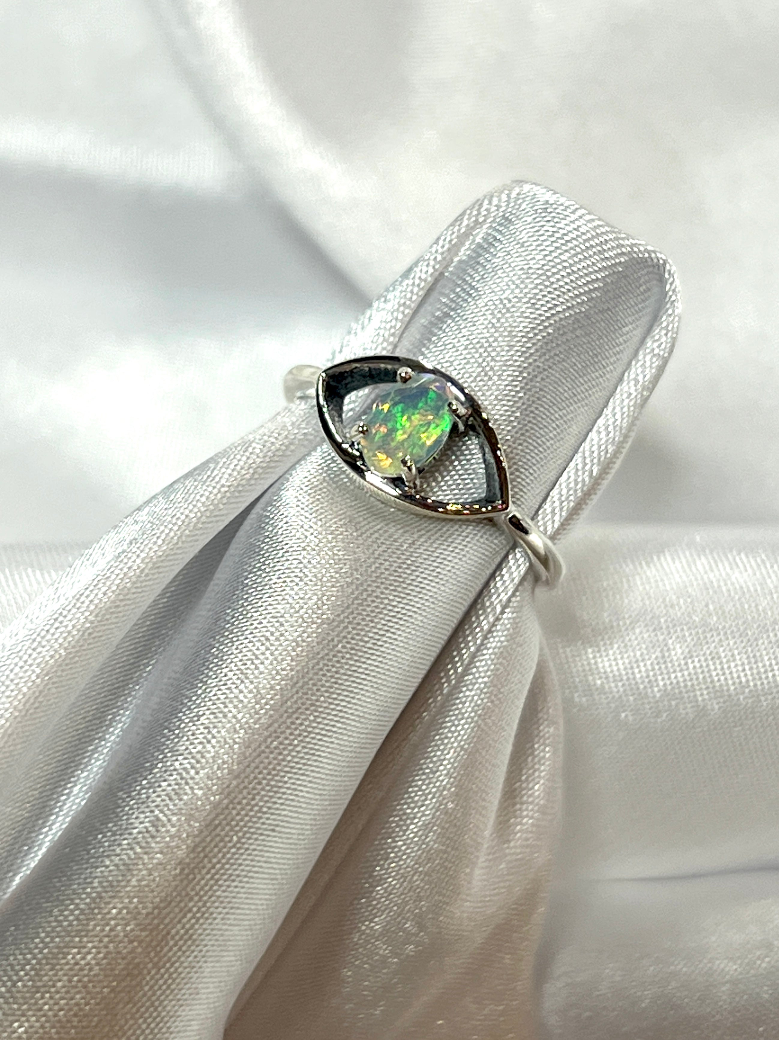 An Facet Cut Ethiopian Opal Evil Eye Ring adorned with an Ethiopian opal, delicately placed on a pristine white cloth.