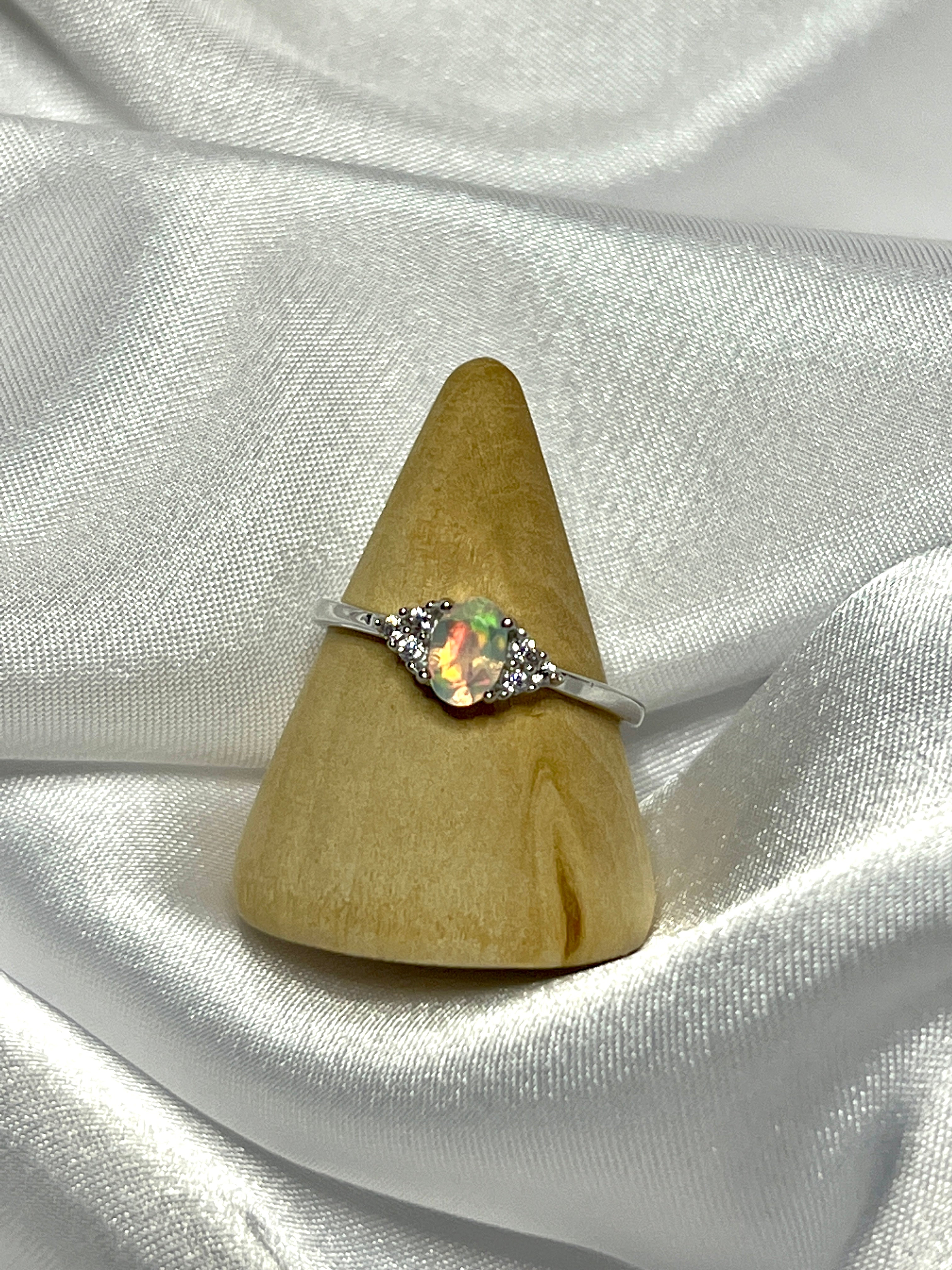 An elegant Ethiopian Opal Ring with Cubic Zirconia Stones on a white cloth.