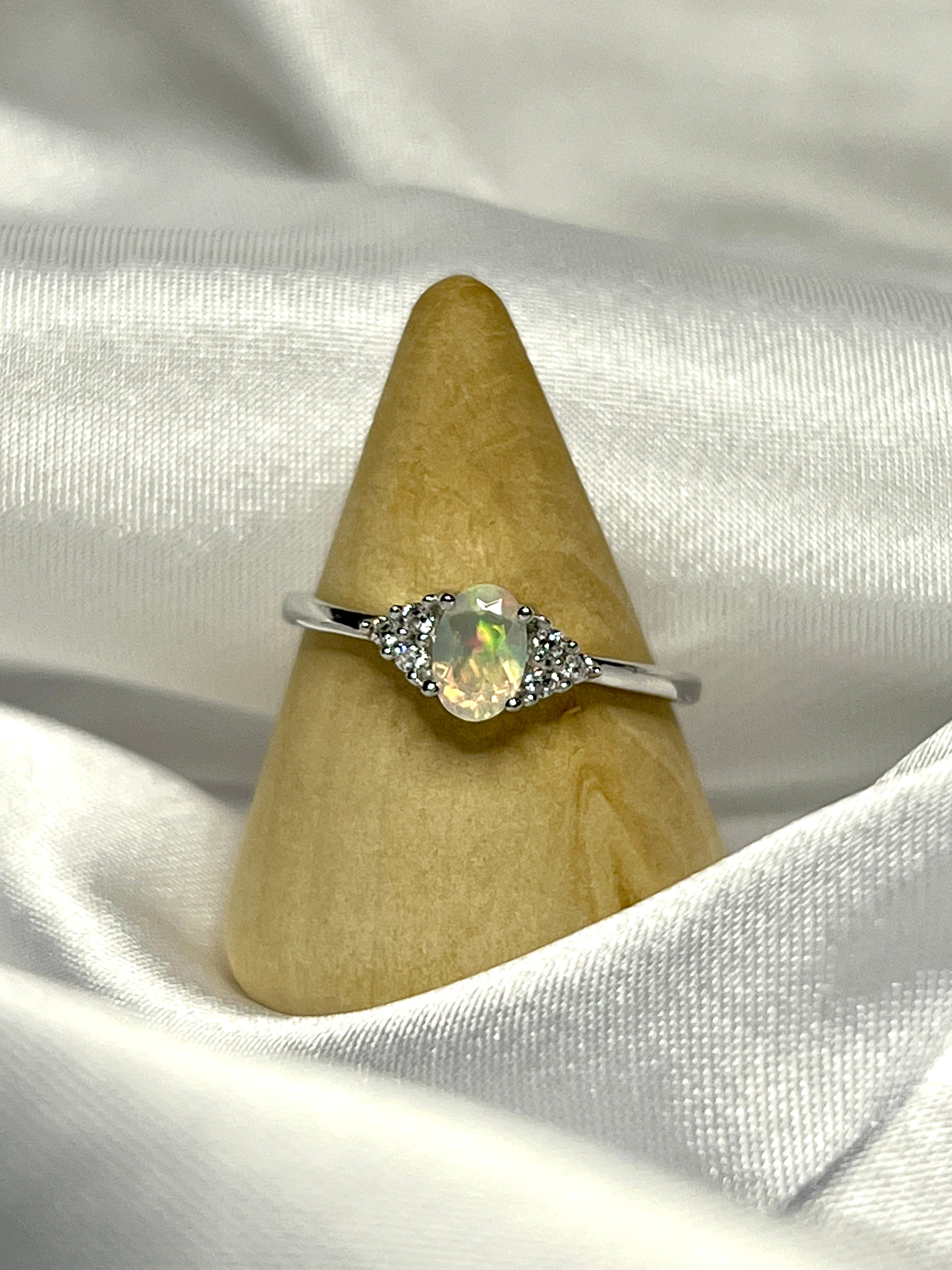 An Ethiopian opal ring with cubic zirconia stones on a white cloth.