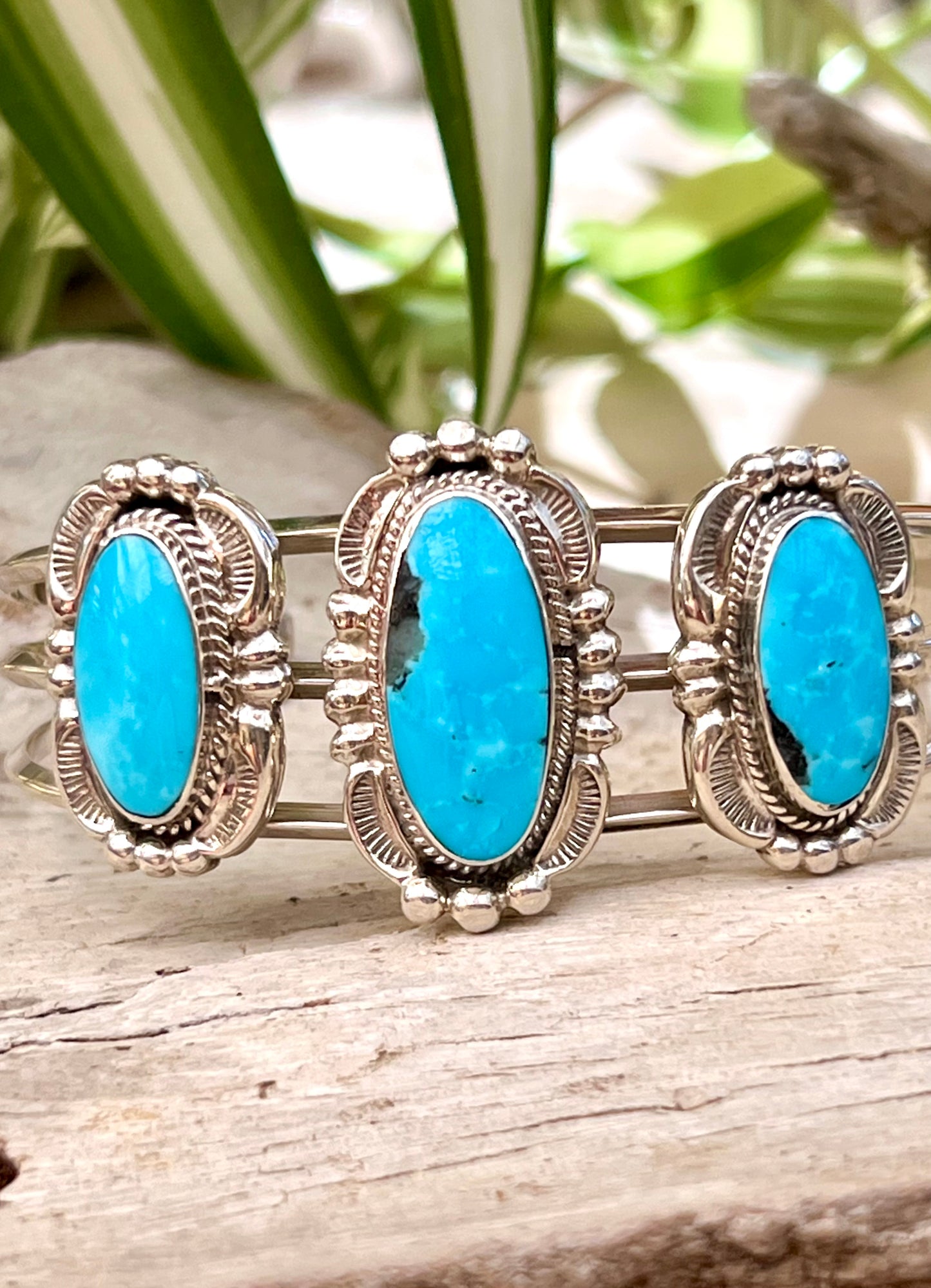 A stunning Super Silver Native American Cuff adorned with three turquoise stones, showcasing intricate silverwork.