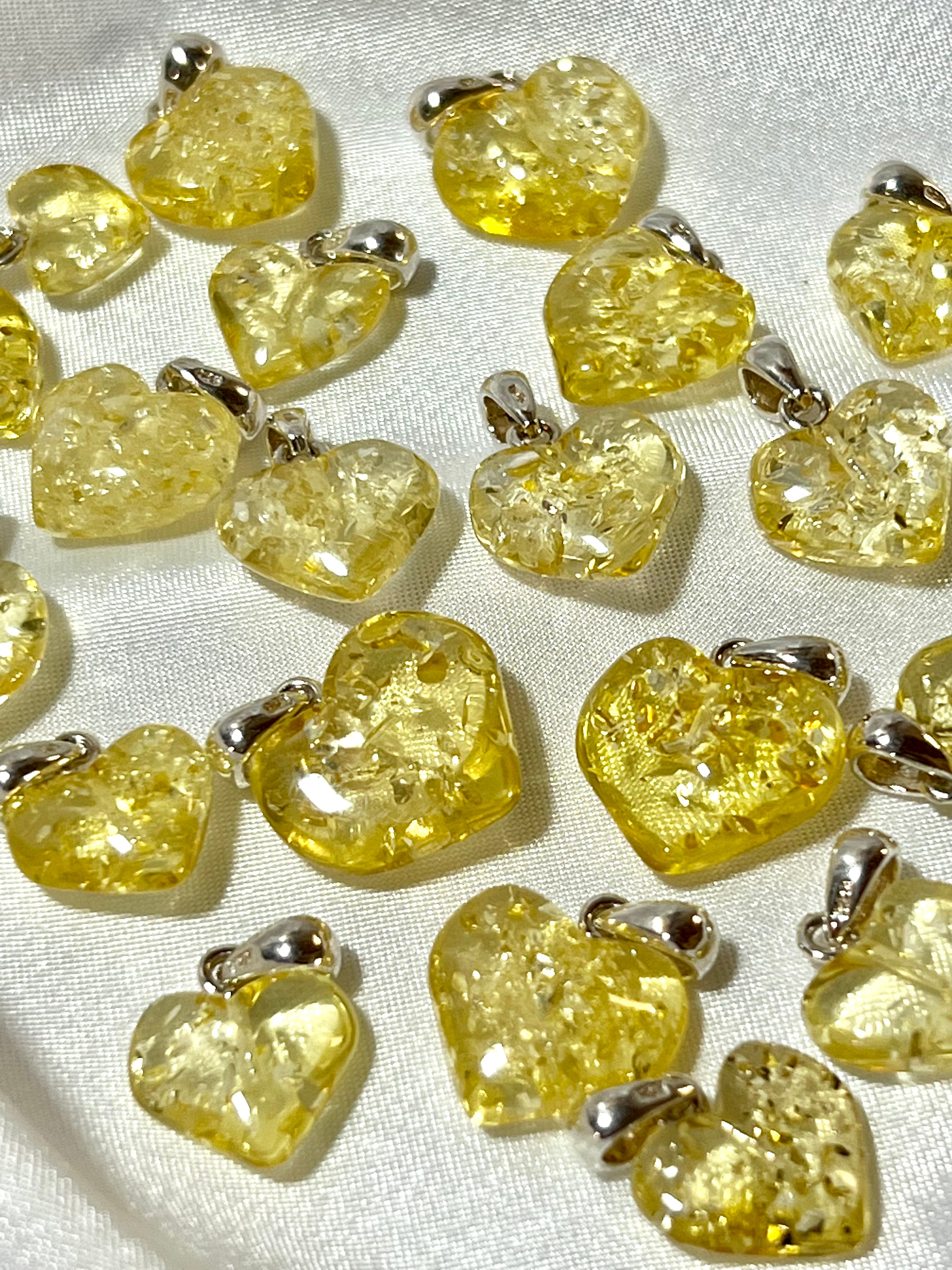 A group of Super Silver Charming Baltic Amber Heart Pendants on a white cloth.