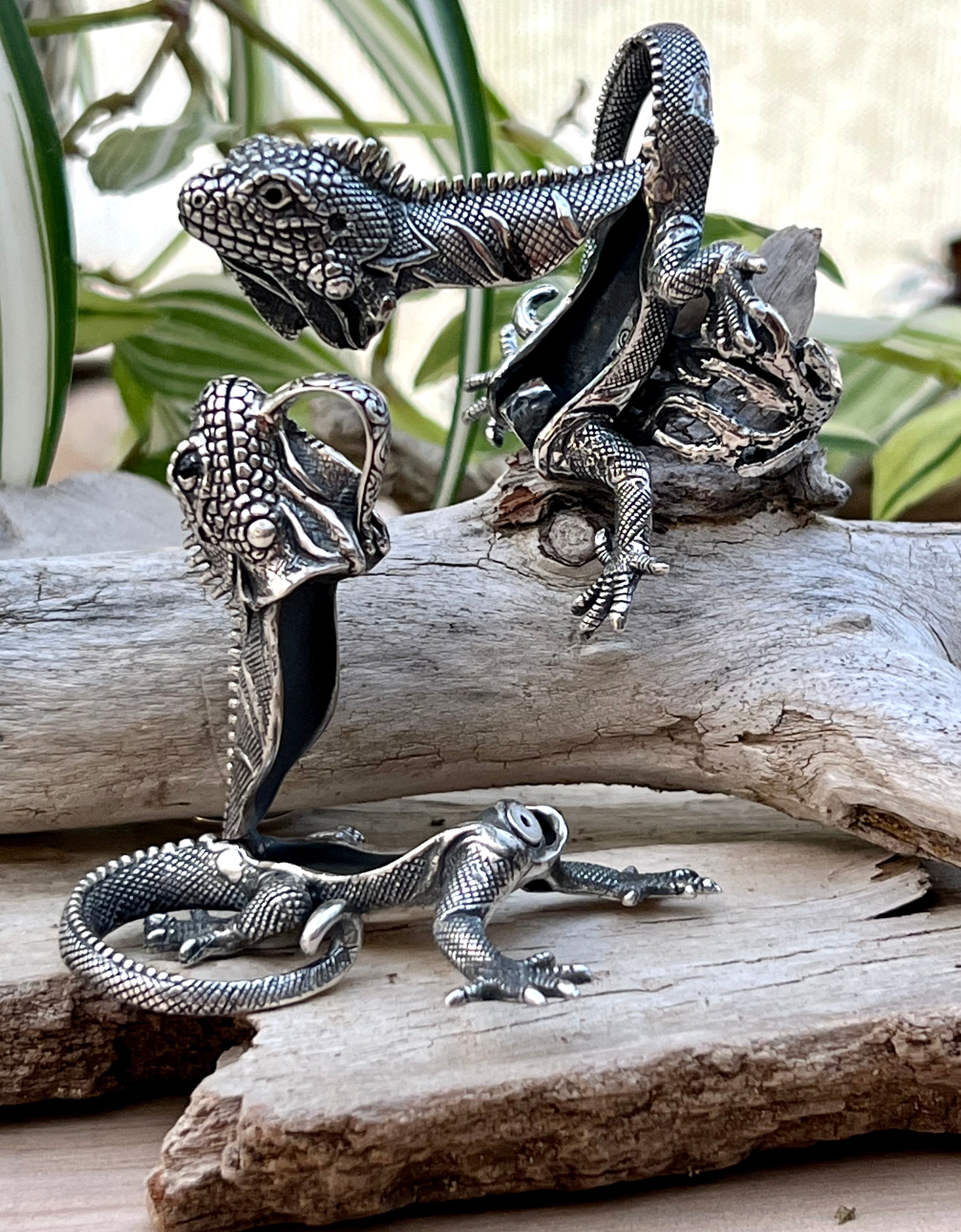 A handcrafted iguana ring sitting on a piece of wood.