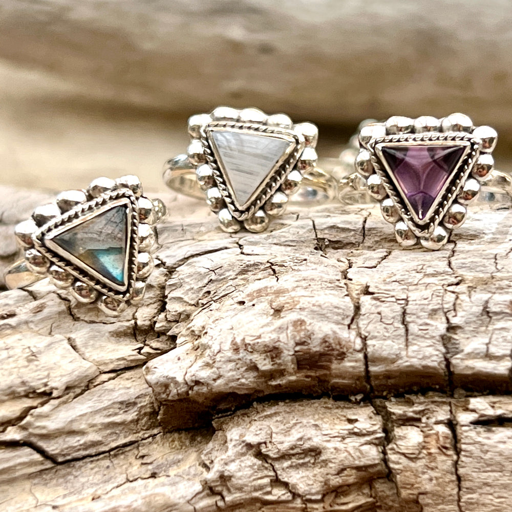 Three Triangle Gemstone Rings with Beads on a piece of wood.