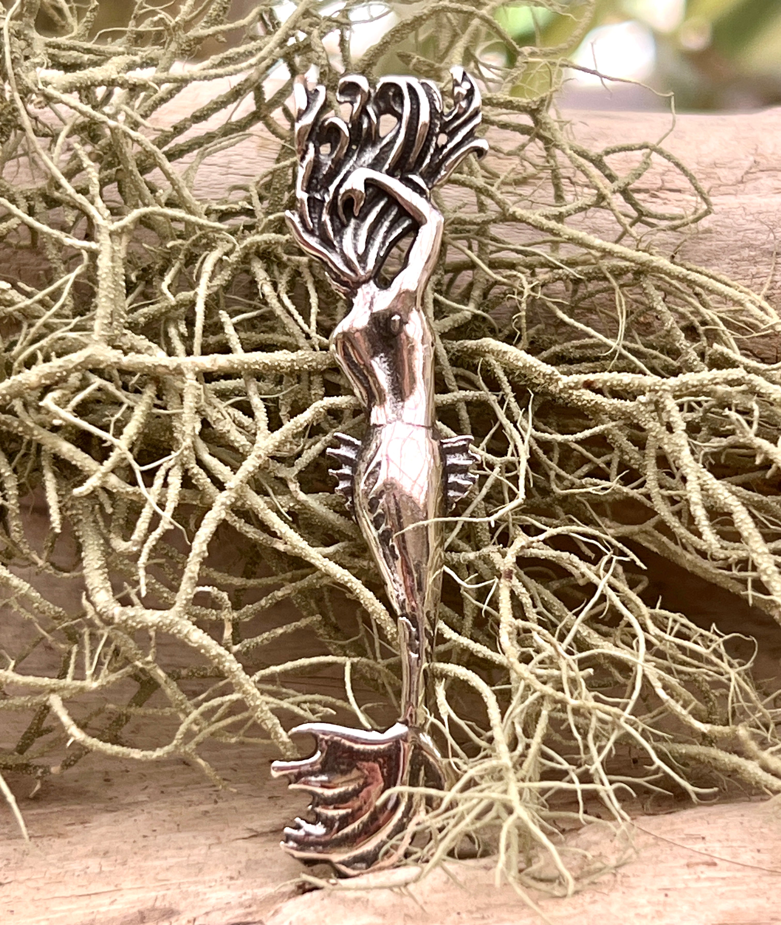 An Enticing Mermaid Pendant by Super Silver is sitting on top of some twigs.