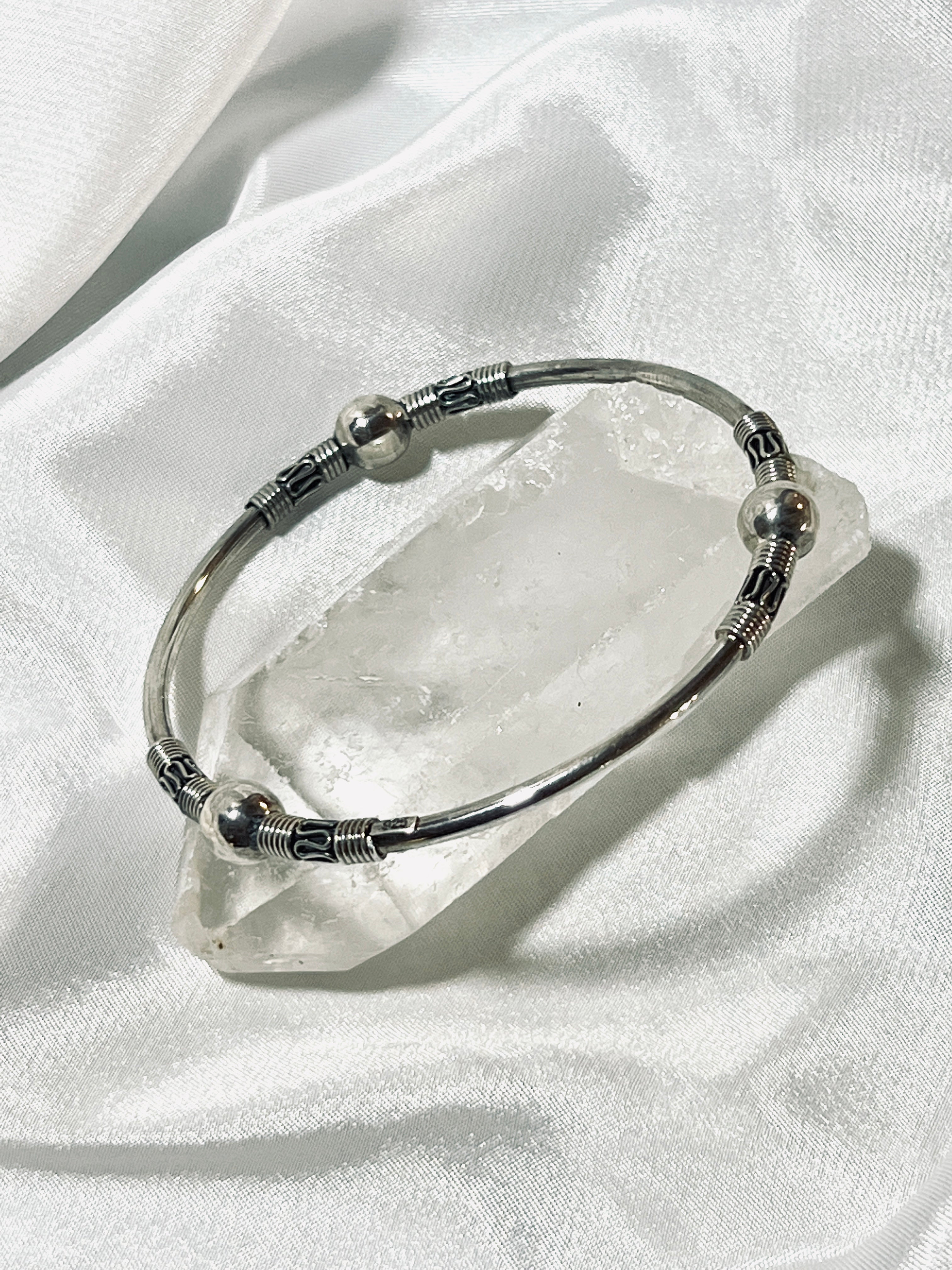 A Super Silver Bali Style Bangle Bracelet resting on a crystal, exuding an earthy boho vibe.