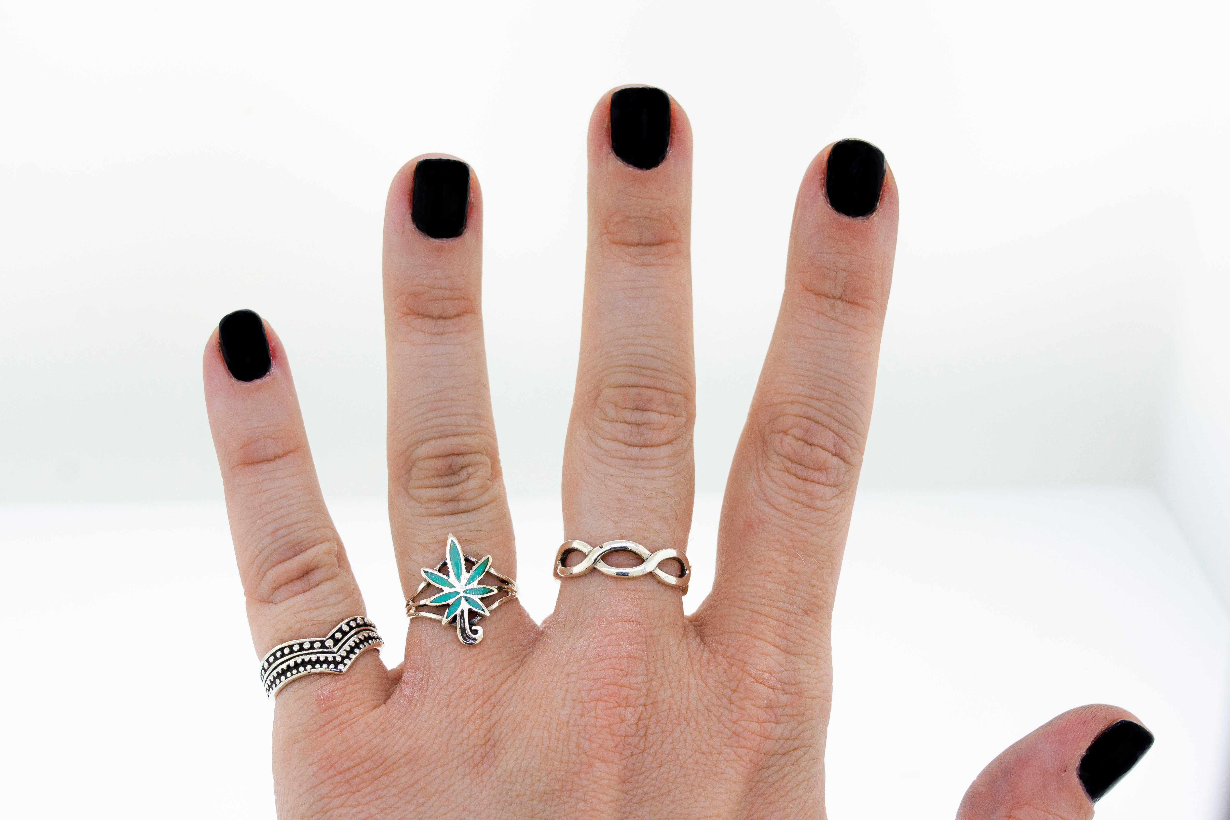 A woman's hand with an Inlay Stone Marijuana Leaf Ring on it.