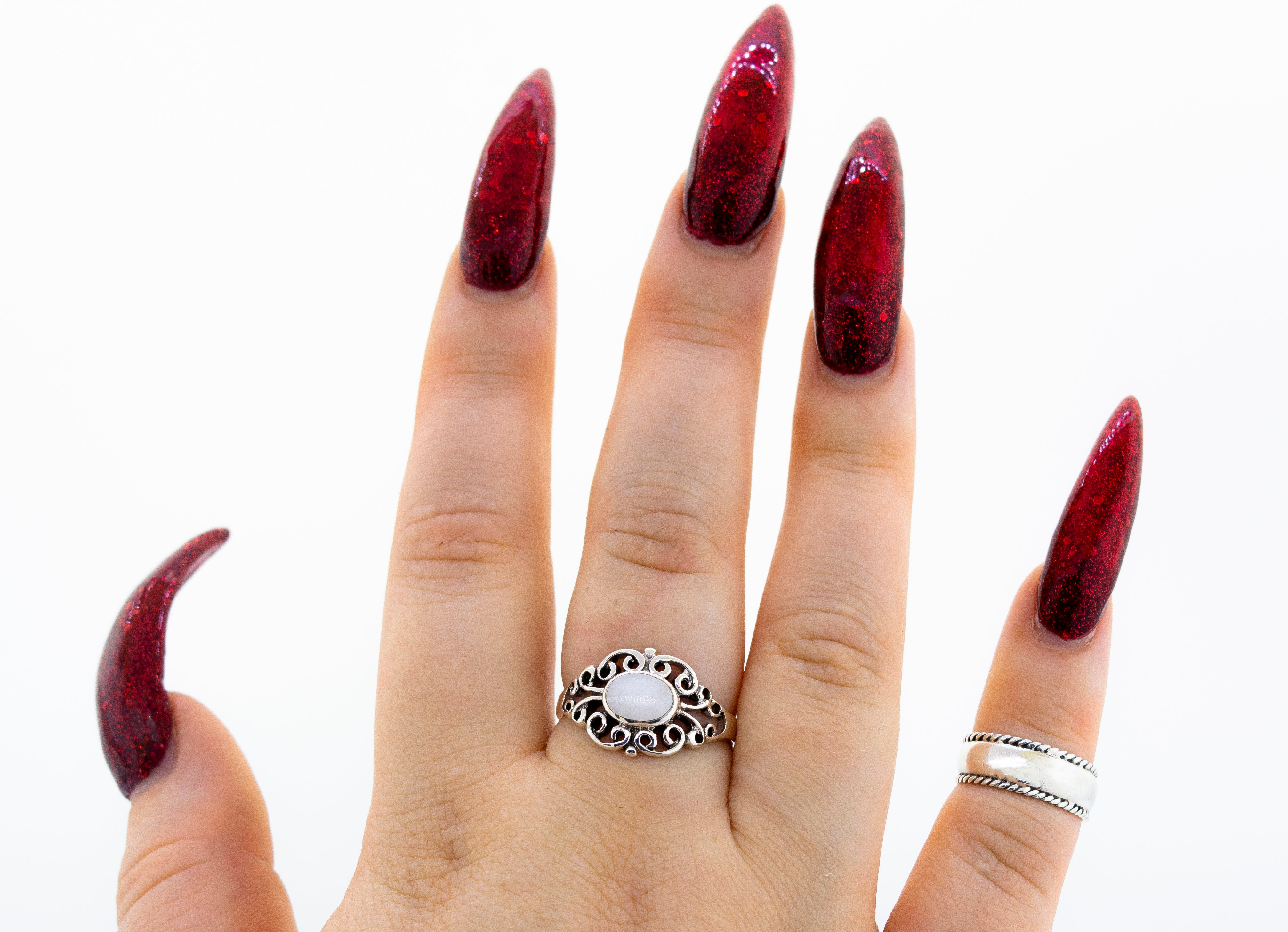 A woman's hand with long red nails and a Victorian Filigree Inlay Stone Ring from Super Silver exudes an elegant style, while maintaining a timeless appeal.