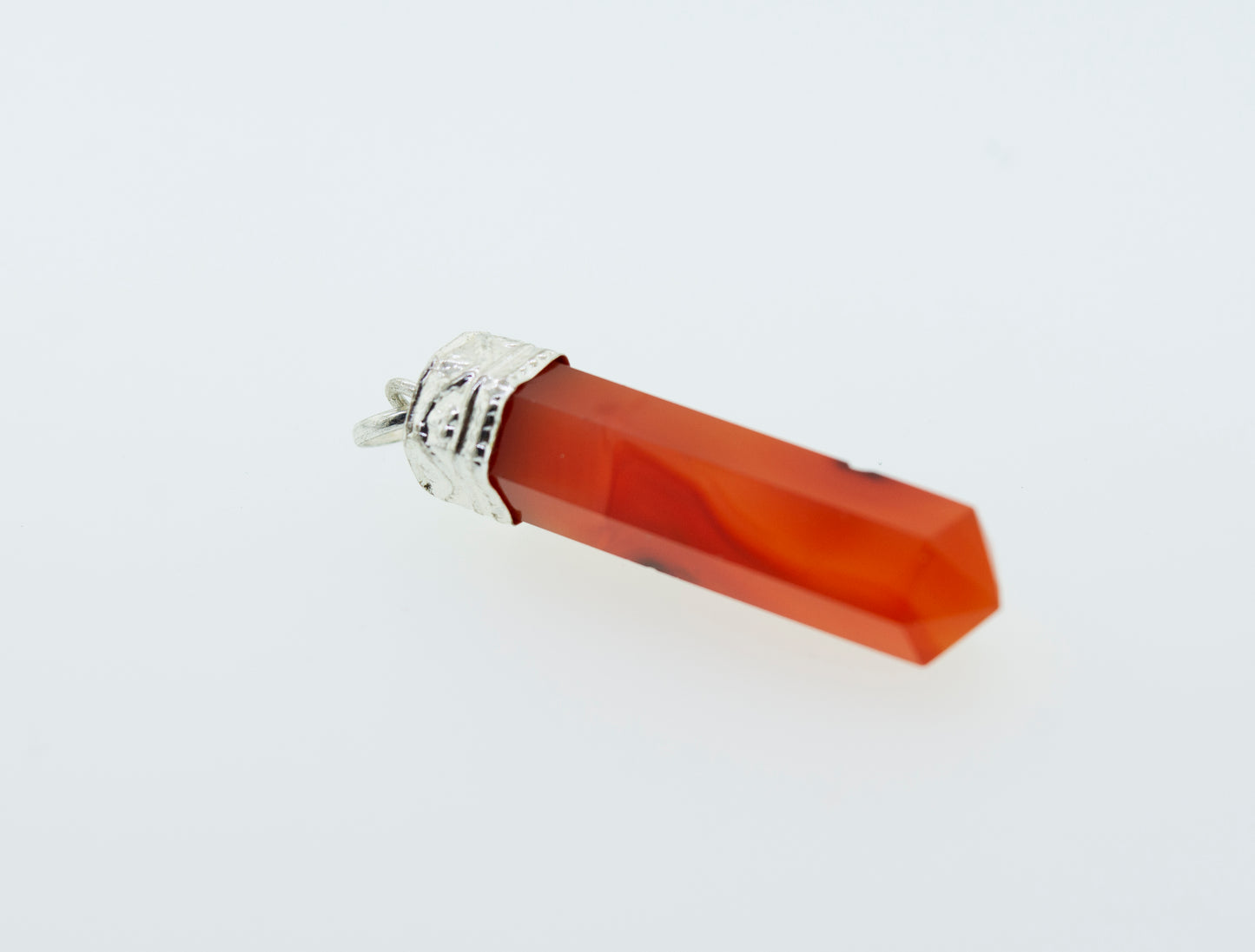 A Raw Stone Obelisk Pendant made of orange jade, perfect for layering with a Super Silver sterling silver chain.
