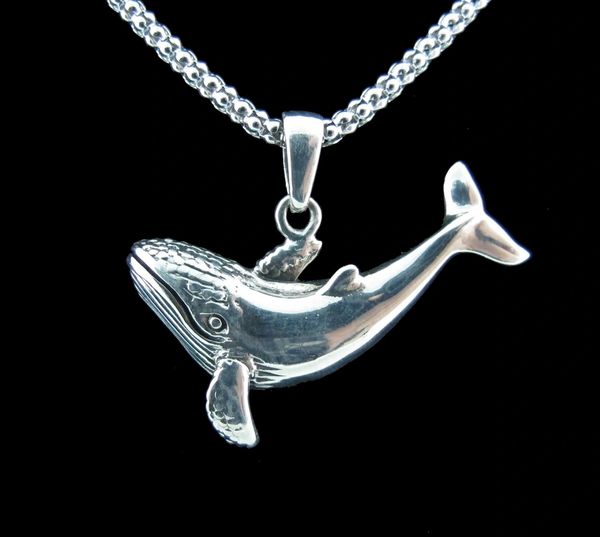 A Super Silver whale pendant on a black background.
