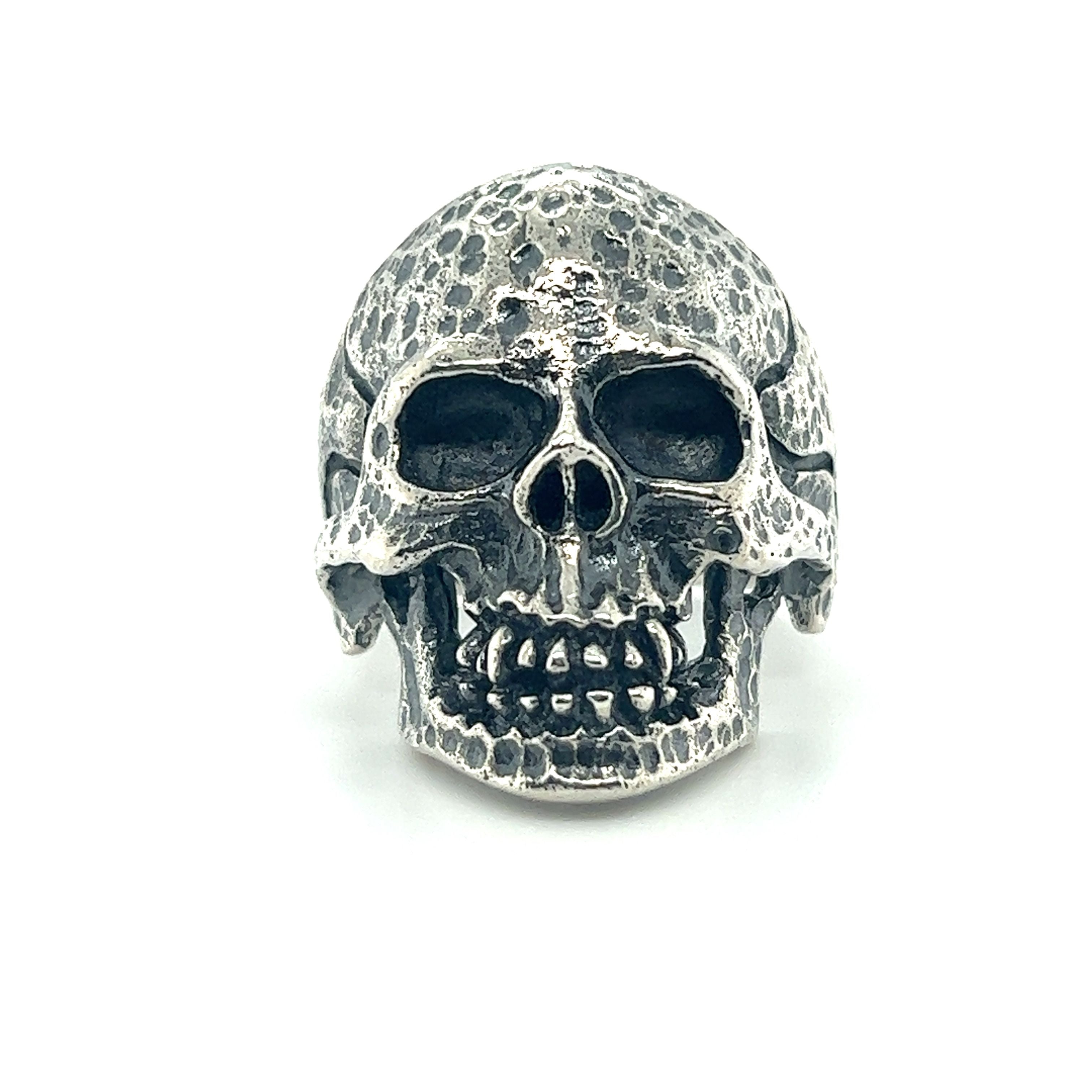 A large textured skull ring on a white background featuring a mens style.