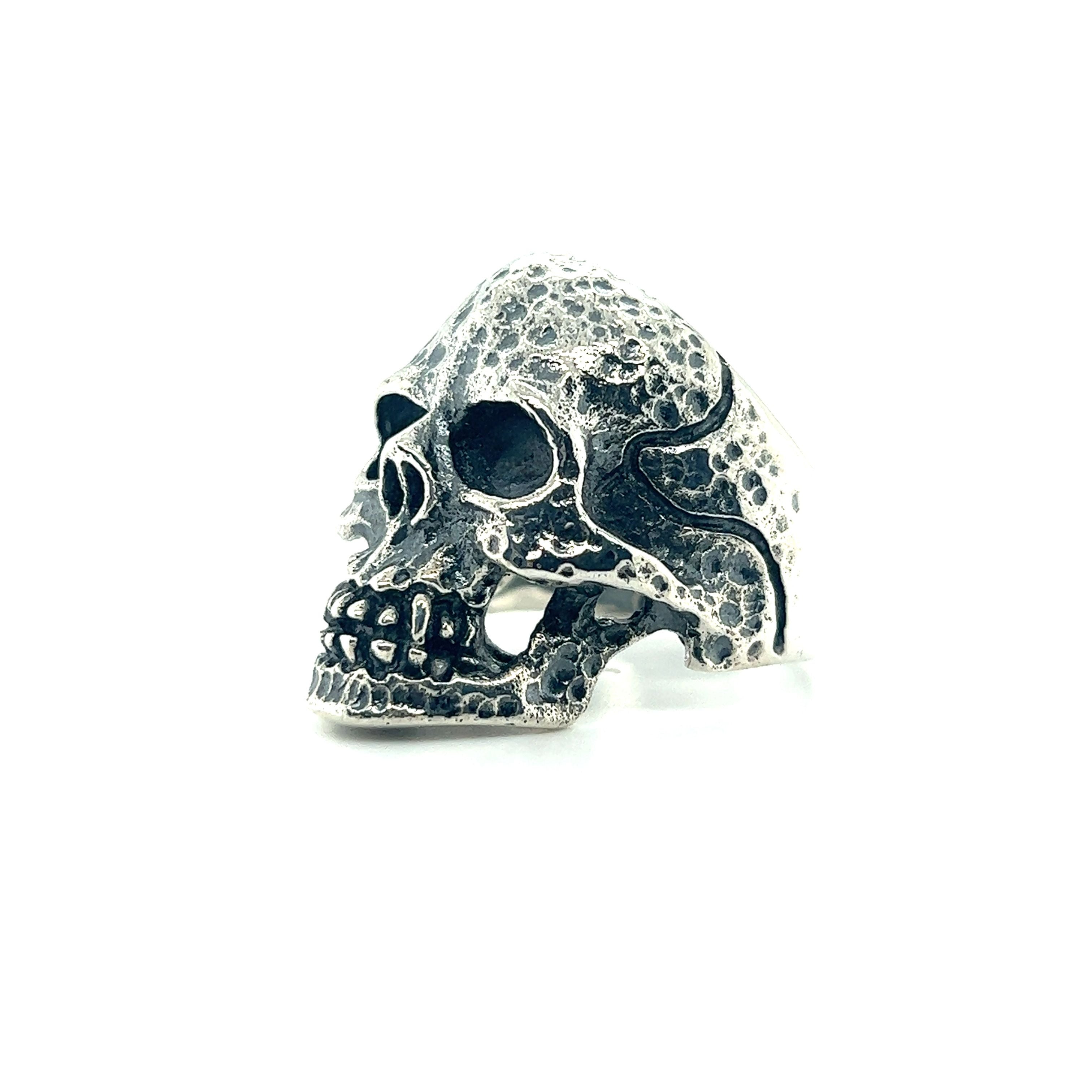 A large textured skull ring on a white background.