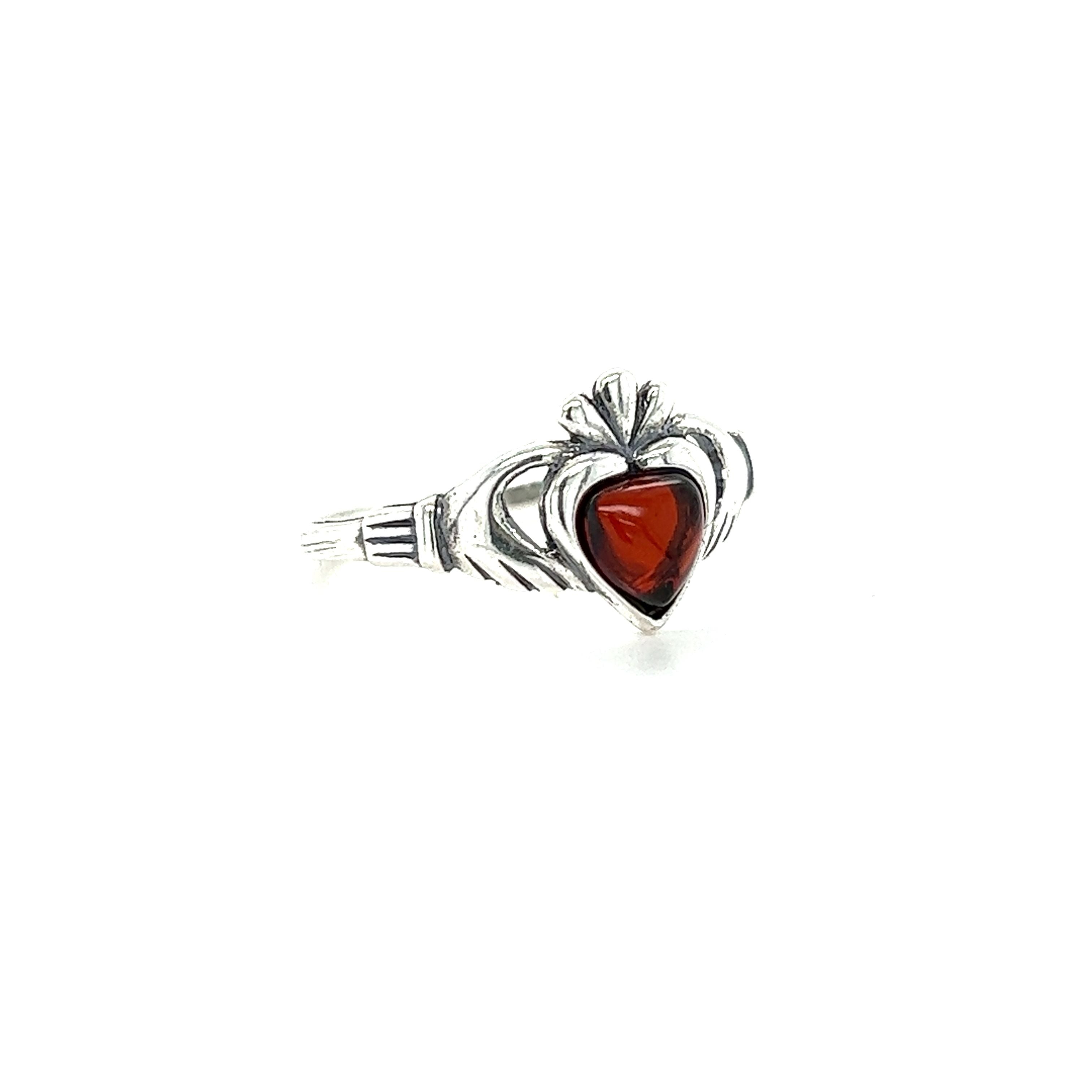 A Super Silver Claddagh Amber Heart Ring with a heart-shaped red stone.