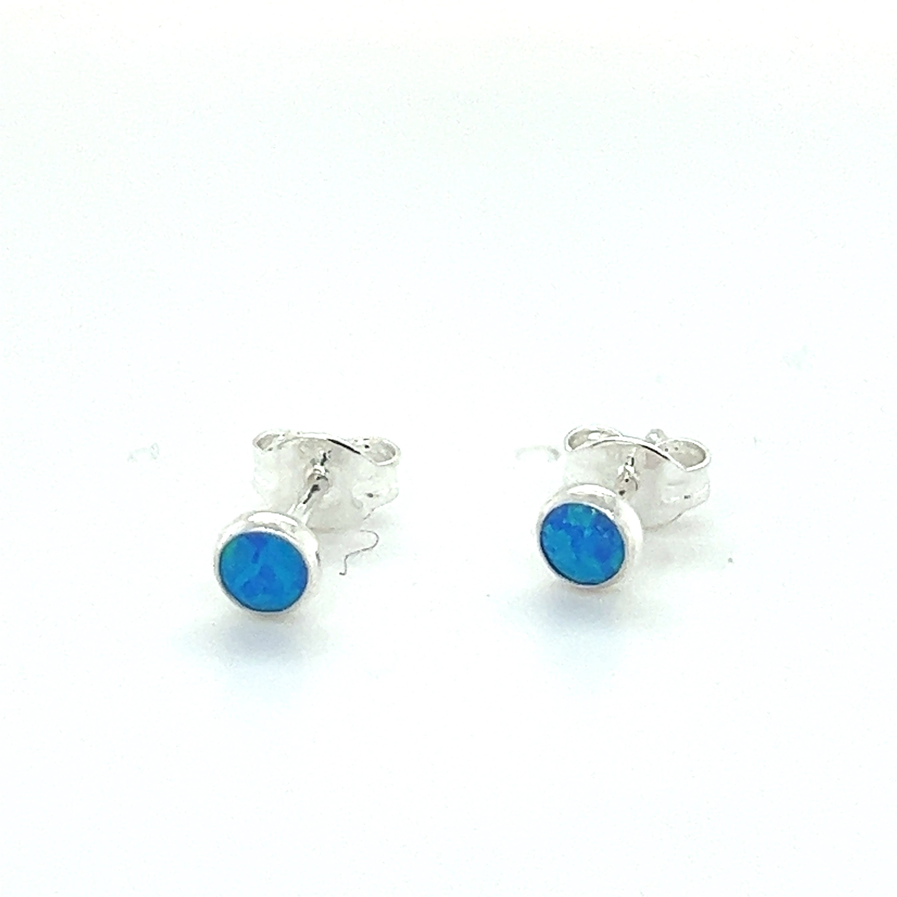 A pair of Super Silver Dainty Opal Studs on a white surface.