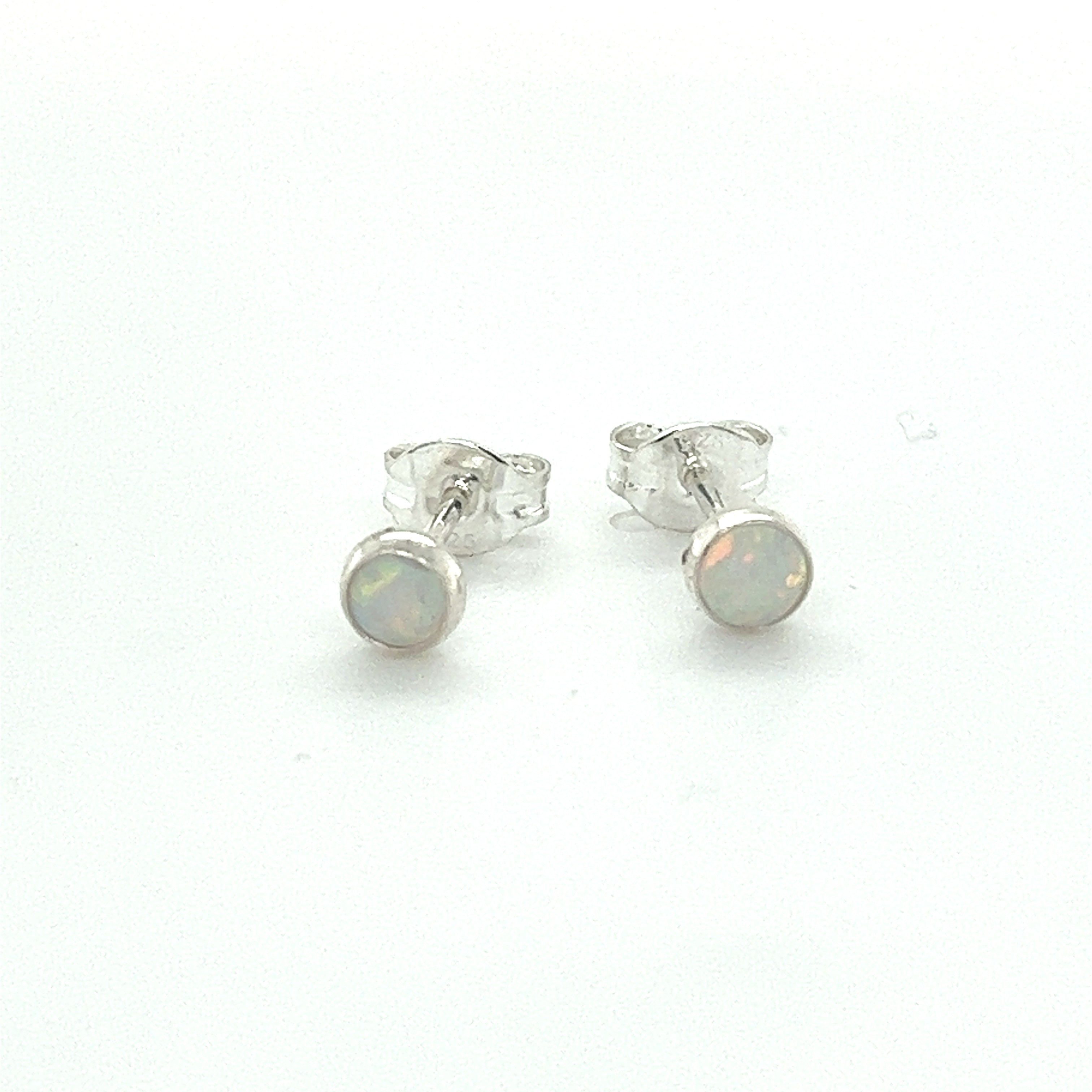 A pair of Dainty Opal Studs by Super Silver with minimalist designs on a white surface.