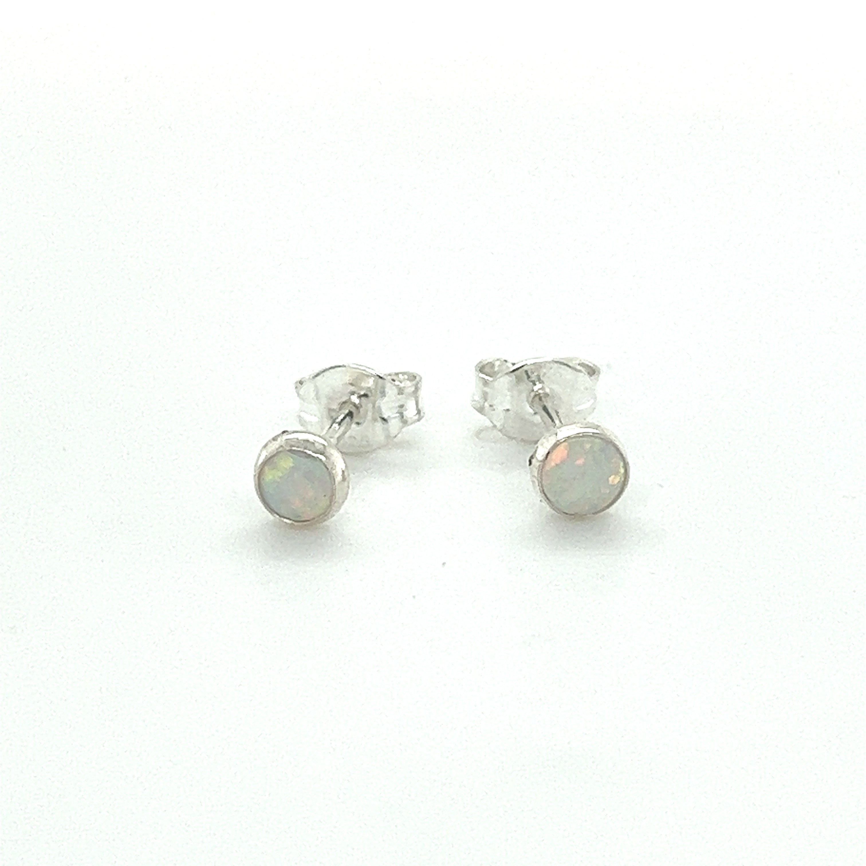 A pair of Dainty Opal Studs from Super Silver with minimalist designs on a white surface.