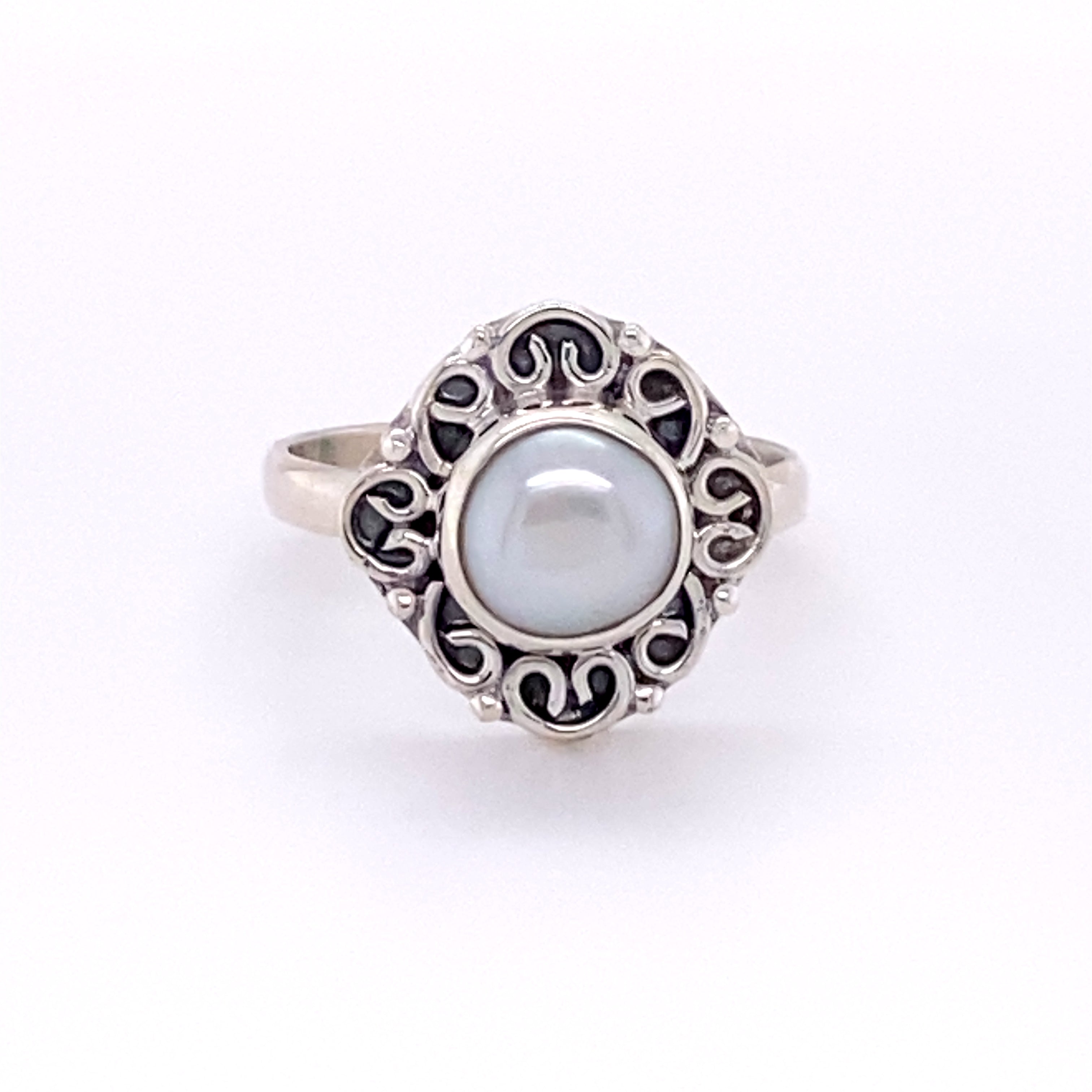 A boho-inspired Oval Gemstone Ring with Swirl Filigree Border in sterling silver with a pearl in the center.
