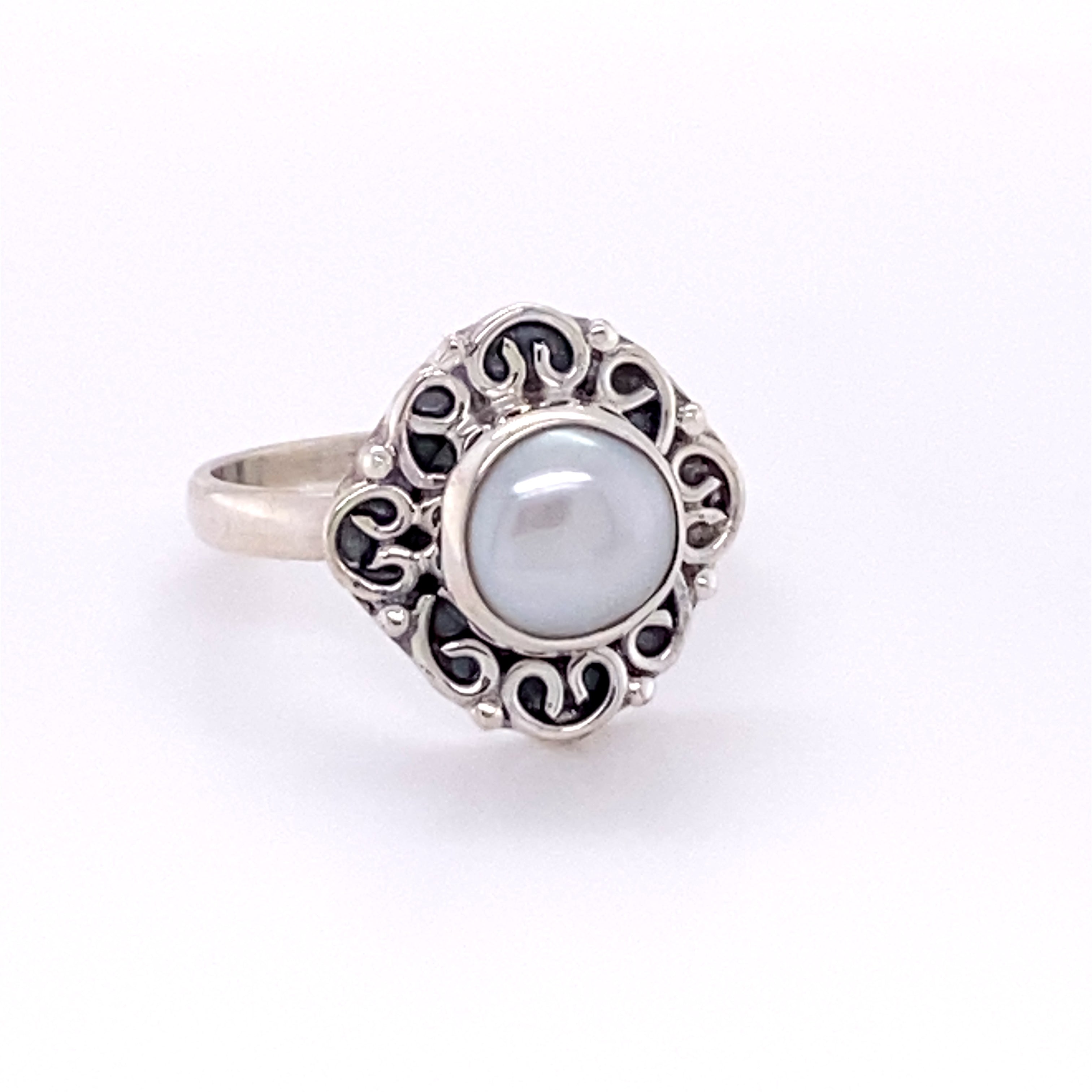 A Oval Gemstone Ring with Swirl Filigree Border with a pearl cabochon in the center.