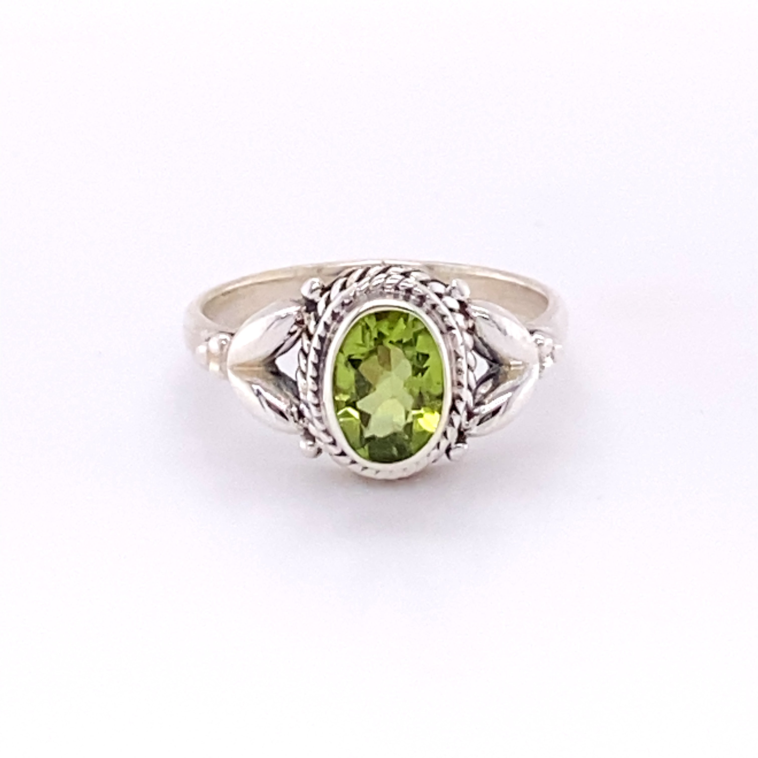 A Super Silver Oval Peridot Ring with Rope Border with a glowing center.