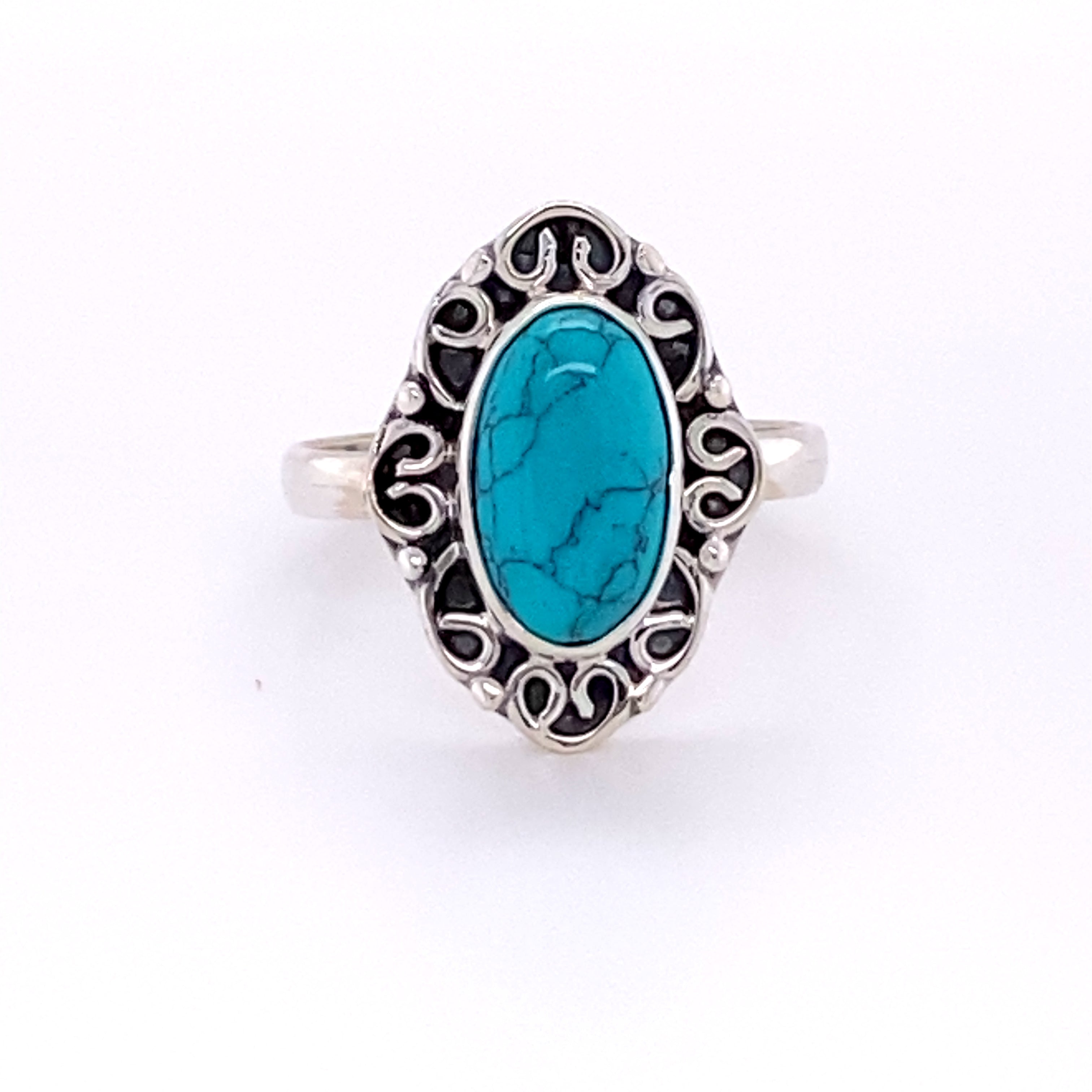 An oval gemstone ring with a swirl filigree border.