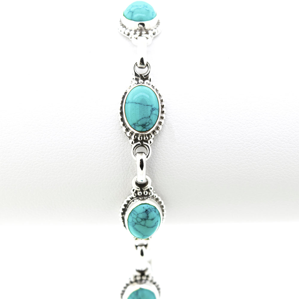 
                  
                    A Super Silver Oval Gemstone Bracelet with Half Ball Border adorned with turquoise gemstones.
                  
                