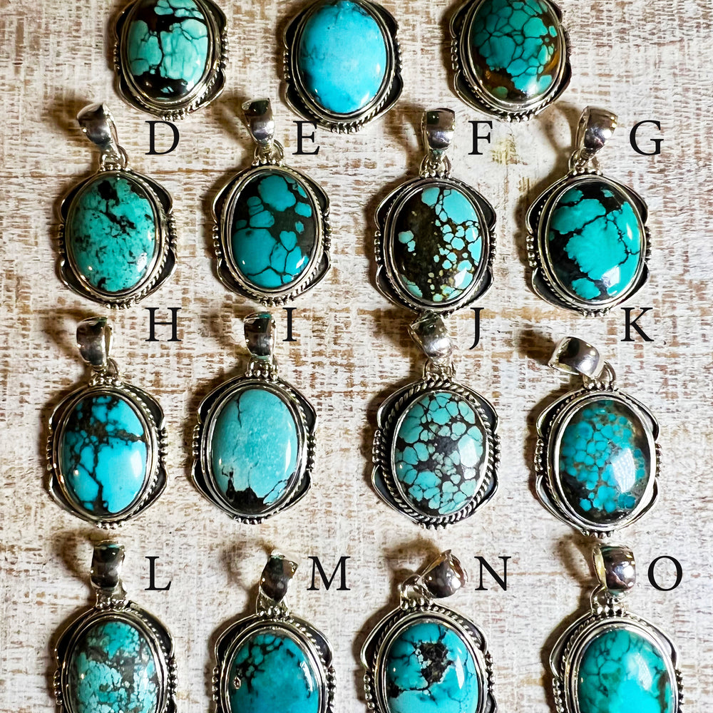 A group of handmade Natural Turquoise Pendants with an Oval Shield Setting from Super Silver on a table.