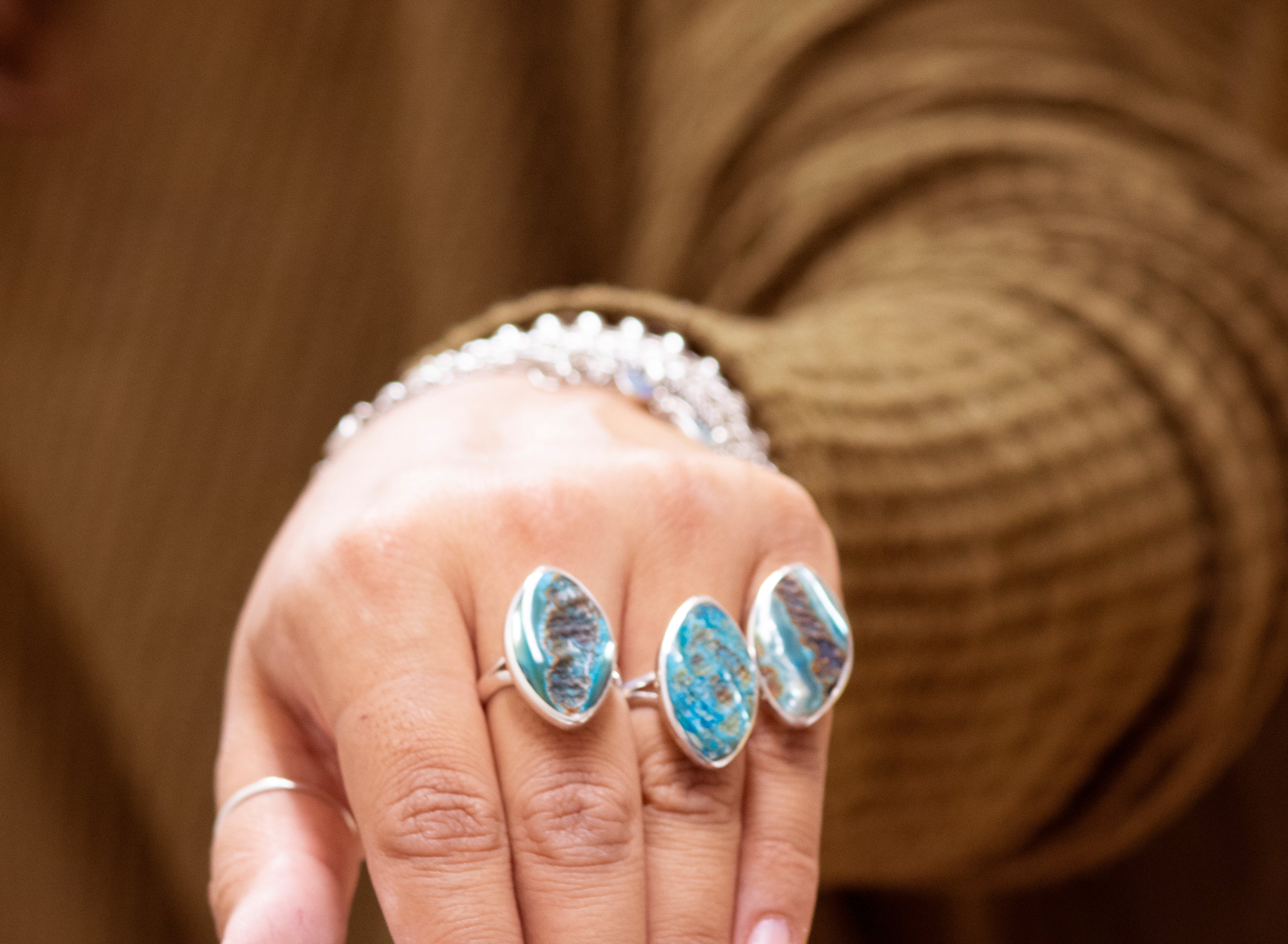 A woman's hand holding a Super Silver Dyed Natural Abalone Ring.