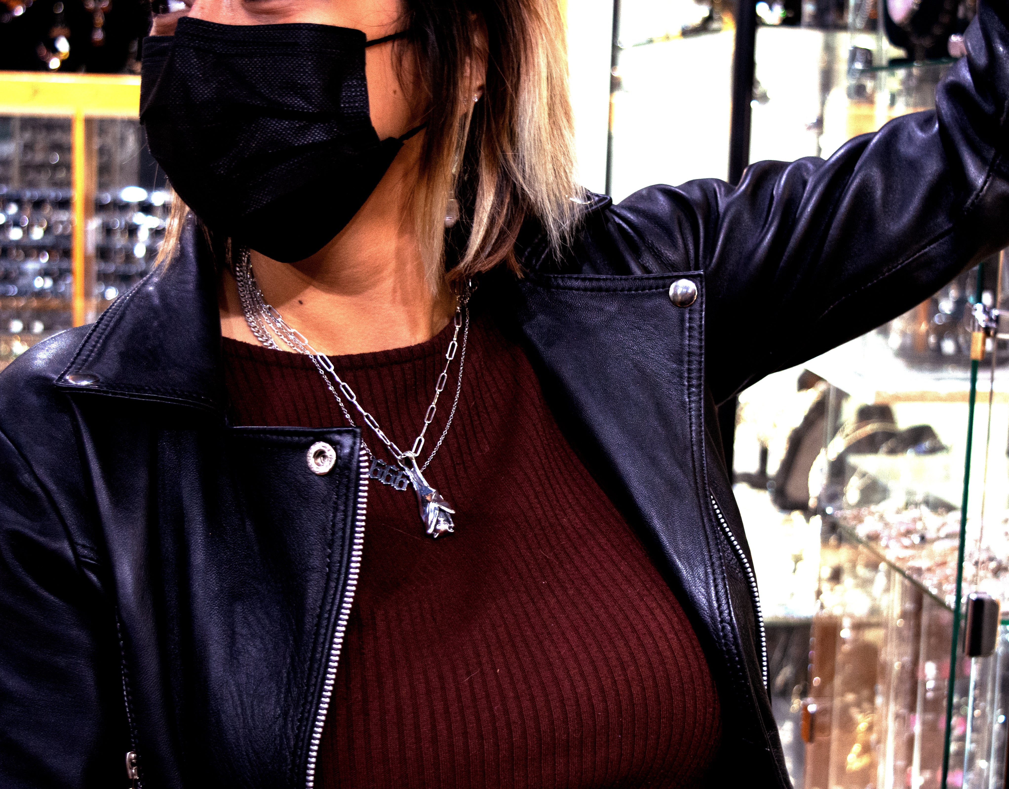 A woman wearing a Super Silver Designer Handcrafted Bat Pendant mask in a jewelry store.