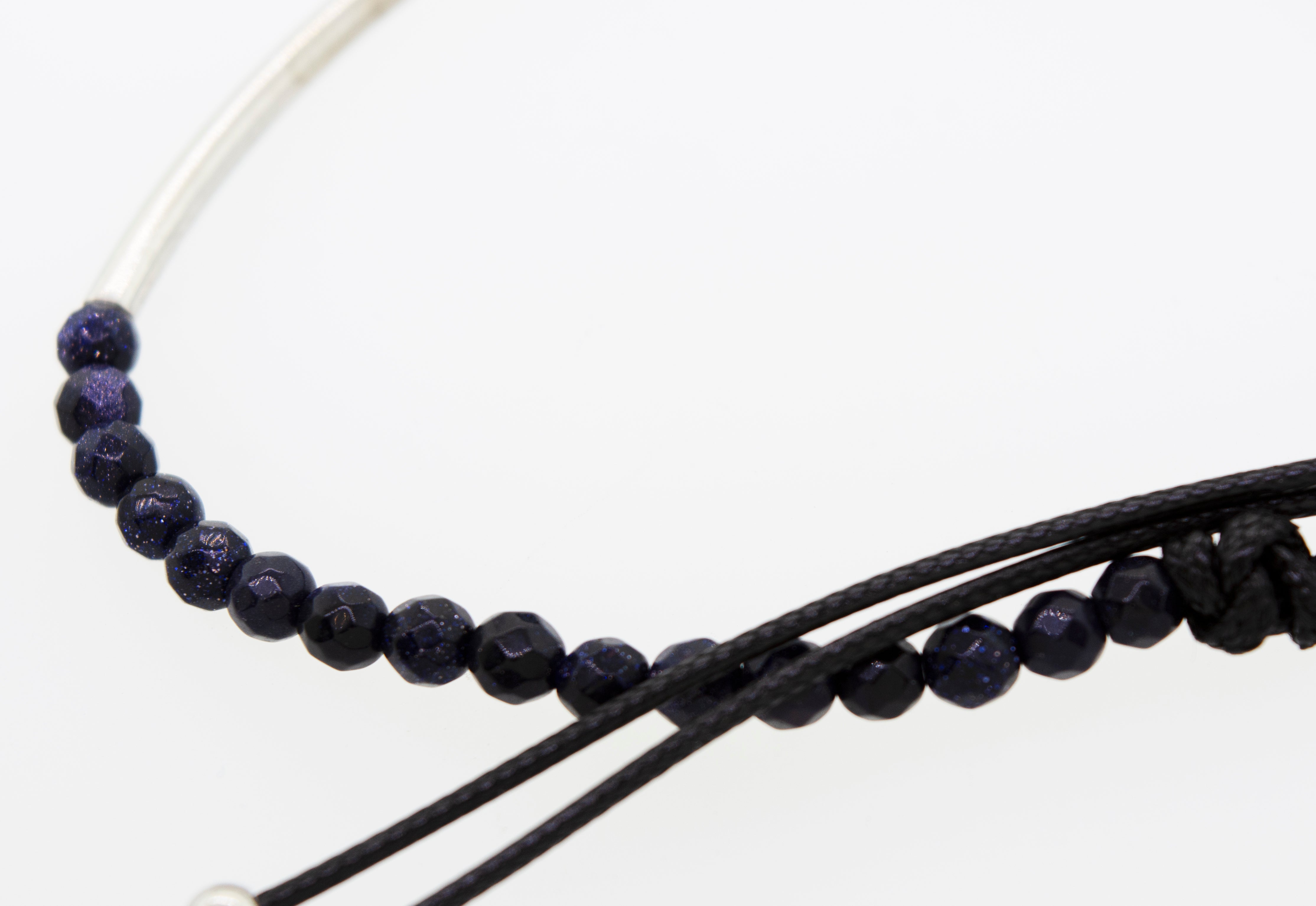 A Super Silver Adjustable Gemstone Bead Bracelet, with black beads and a black cord, highlighted by a silver bar.