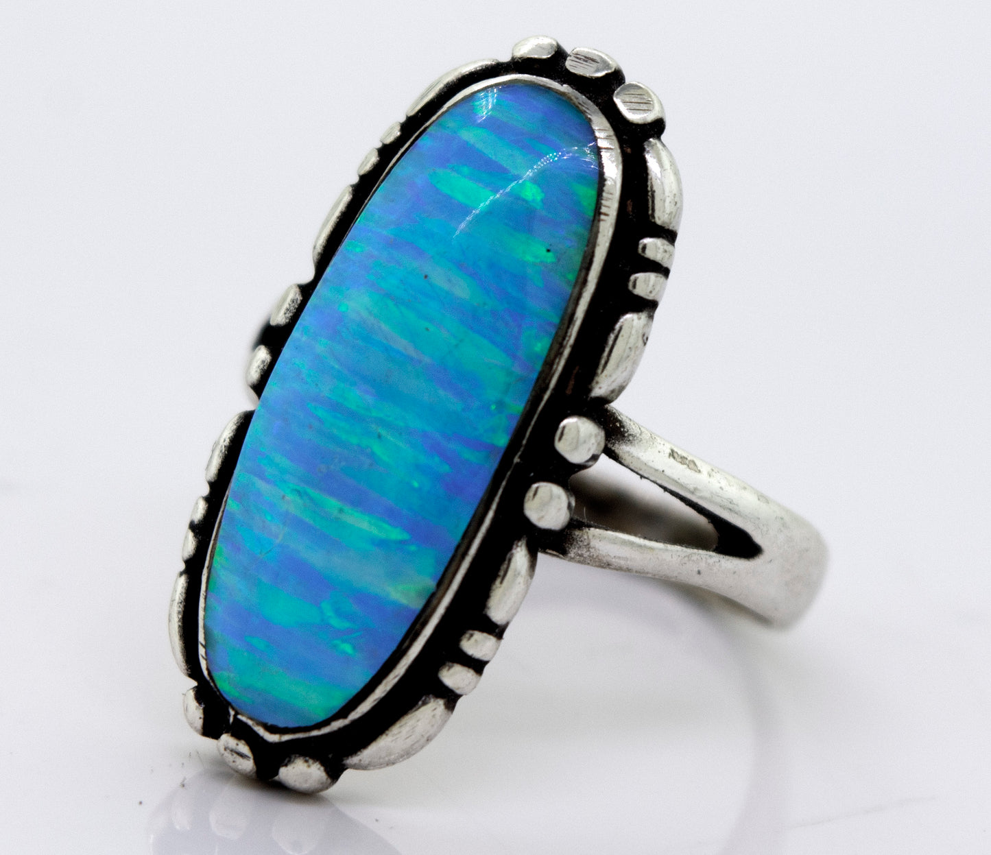 
                  
                    A Super Silver American Made Oval Opal Ring with a blue opal stone in a southwestern-styled design.
                  
                